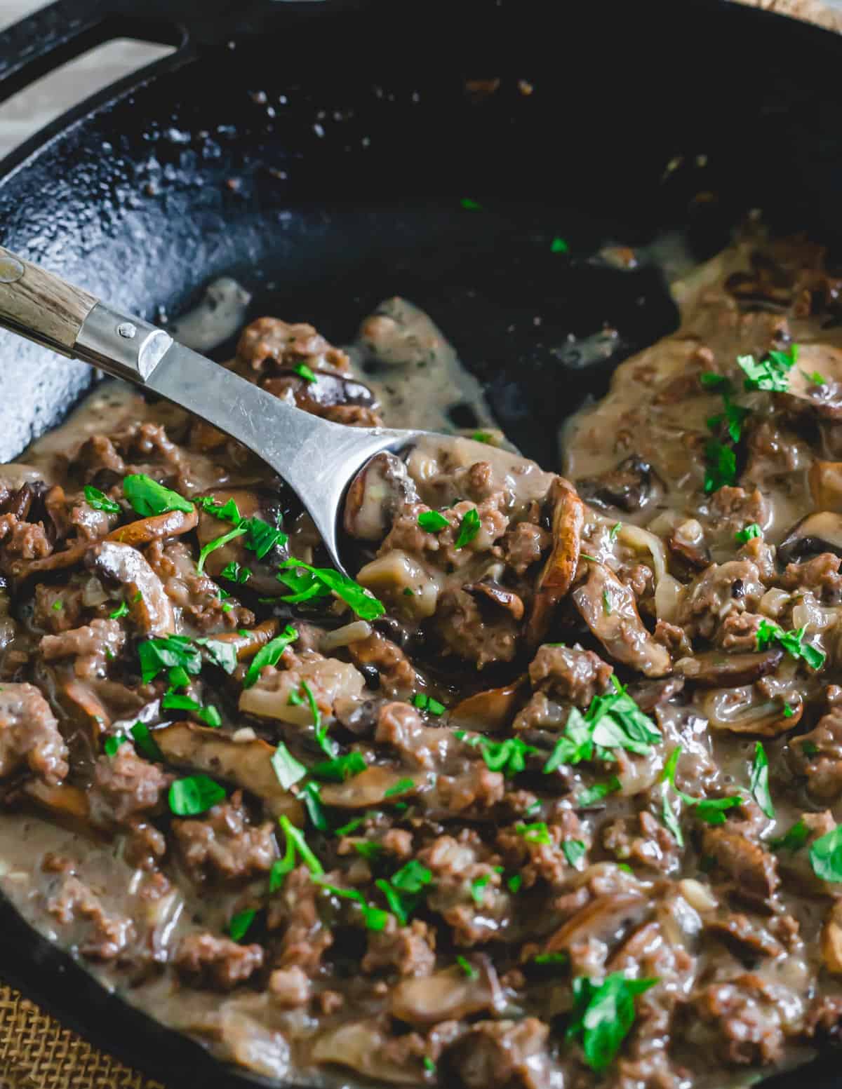 Close up of venison stroganoff recipe in a skillet with a metal spoon.