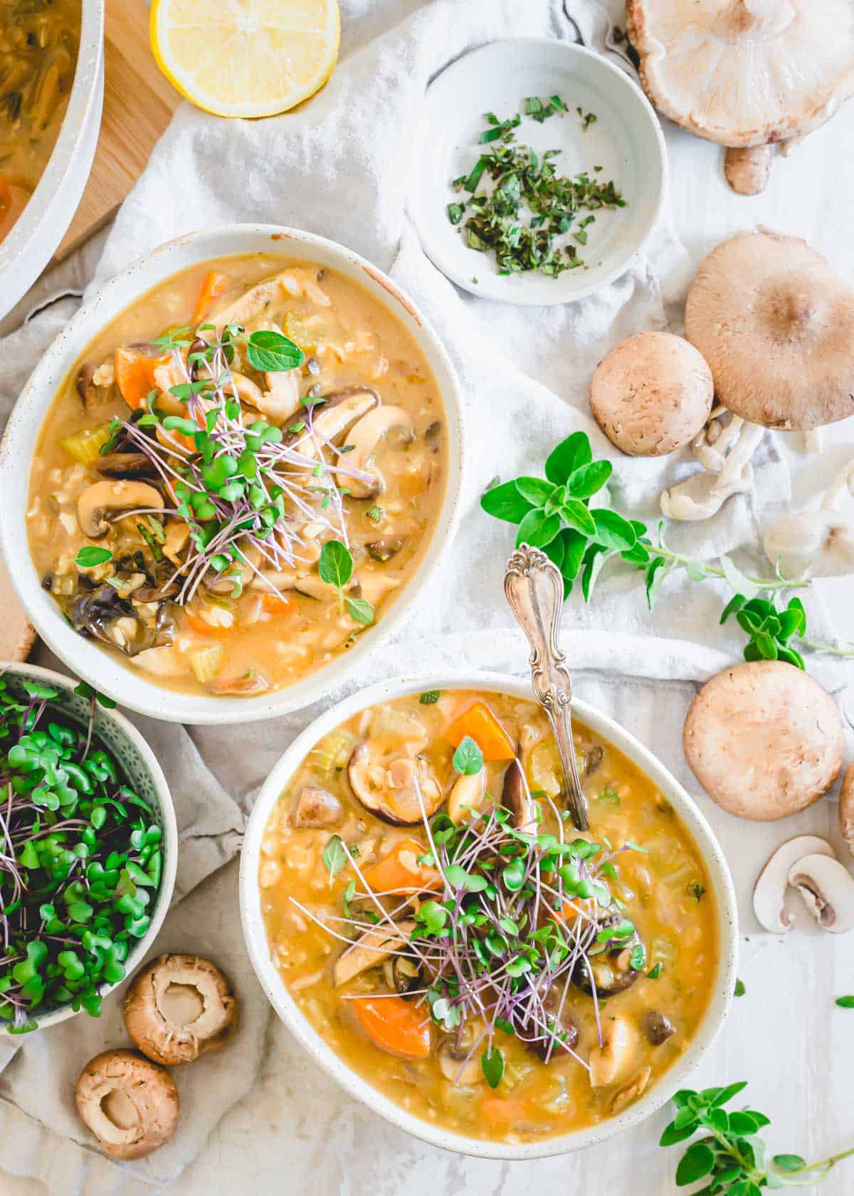 Wild mushroom soup recipe garnished with micro-greens in bowls with spoons.