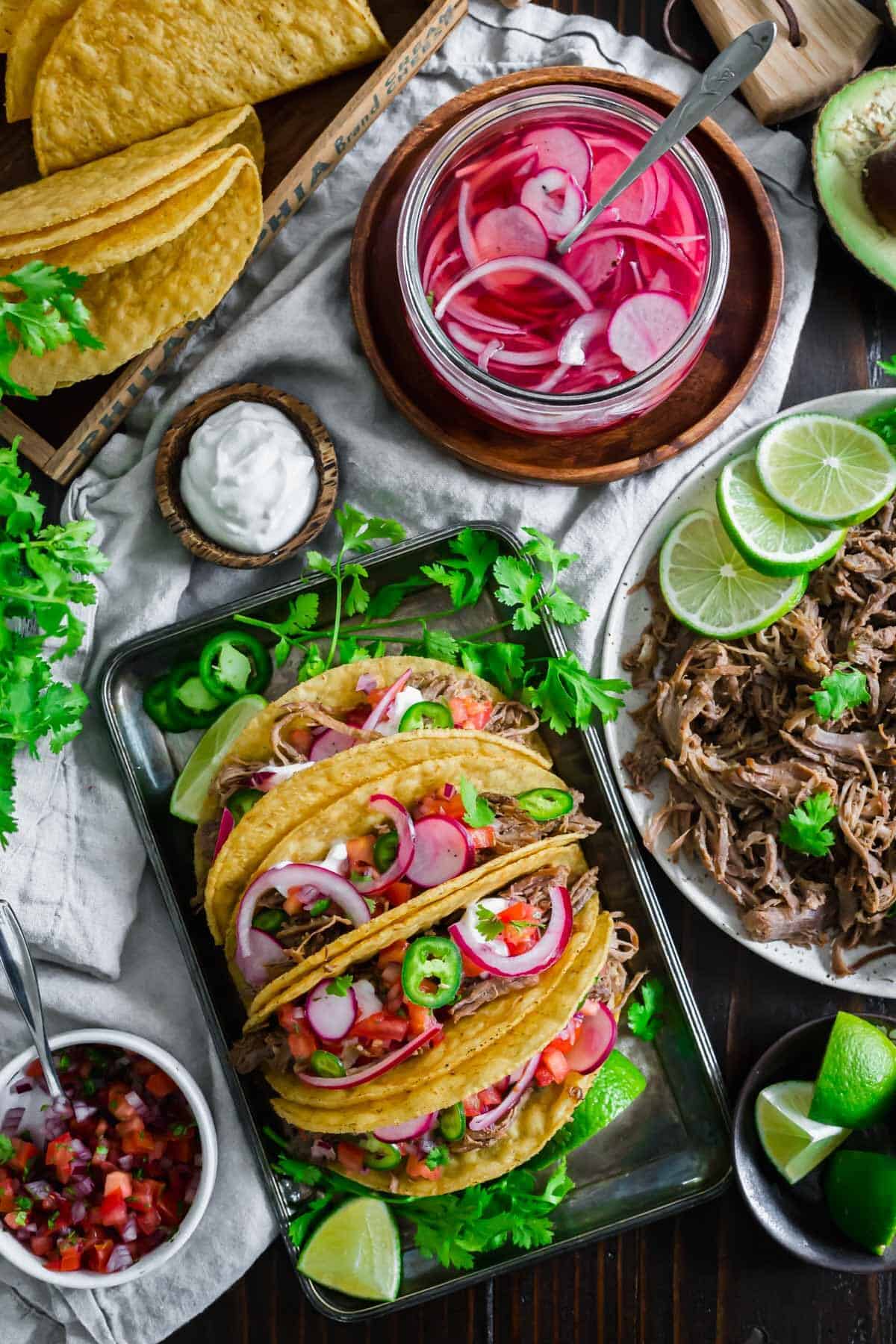 Lamb tacos with shredded lamb on the side and taco toppings.