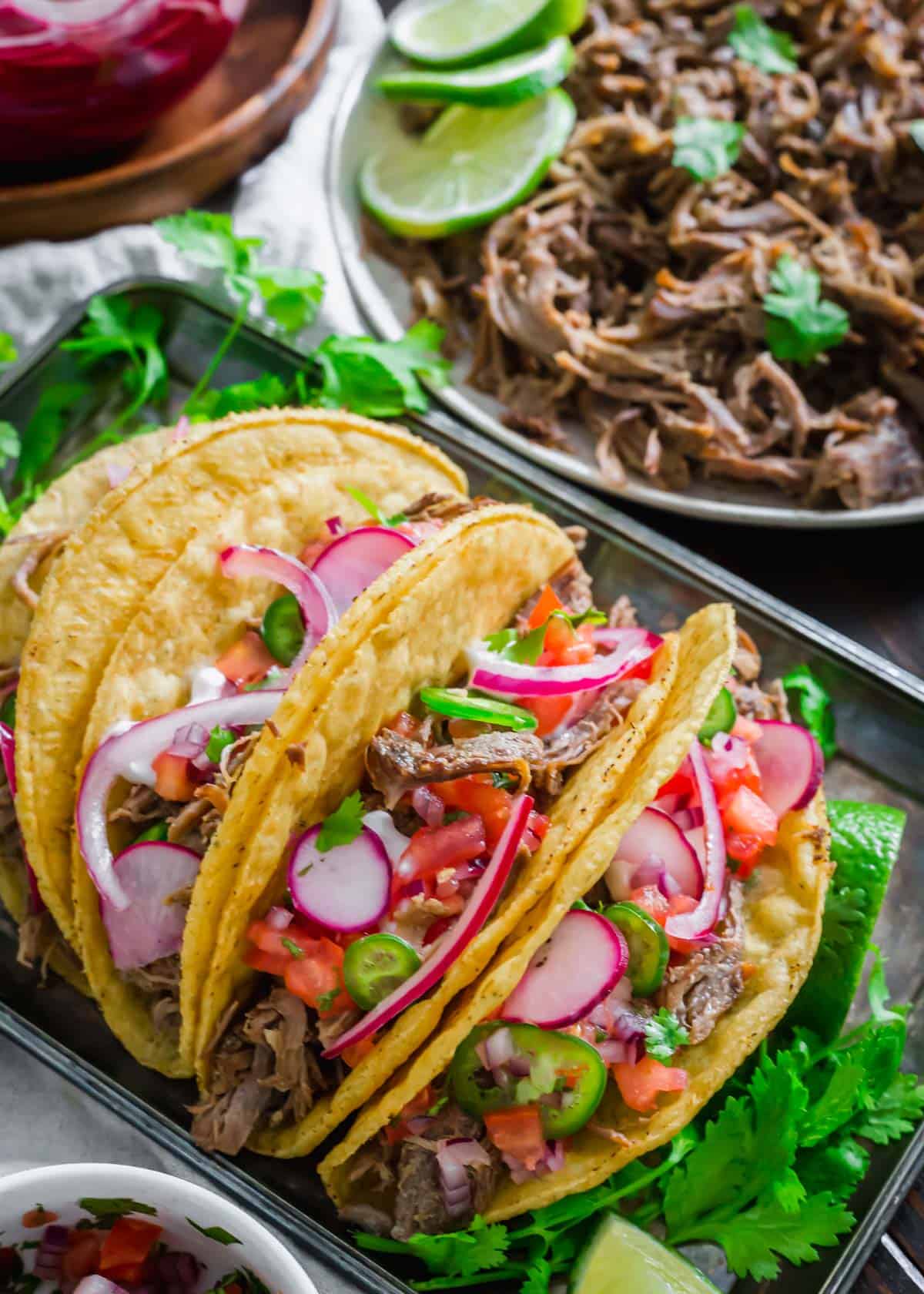 Lamb tacos in hard tacos shells on a platter.