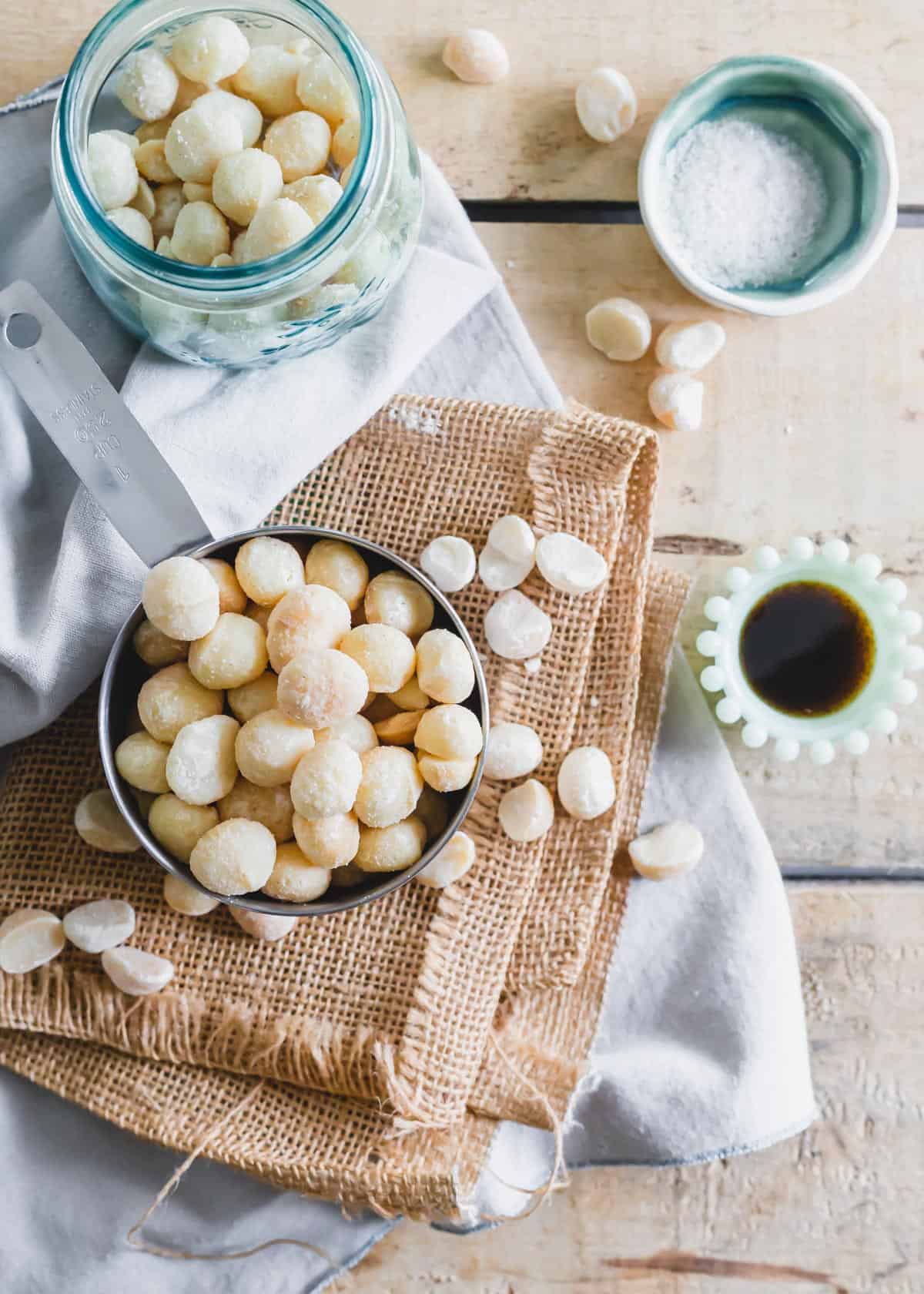 Raw macadamia nuts in a measuring cup with vanilla and sea salt.