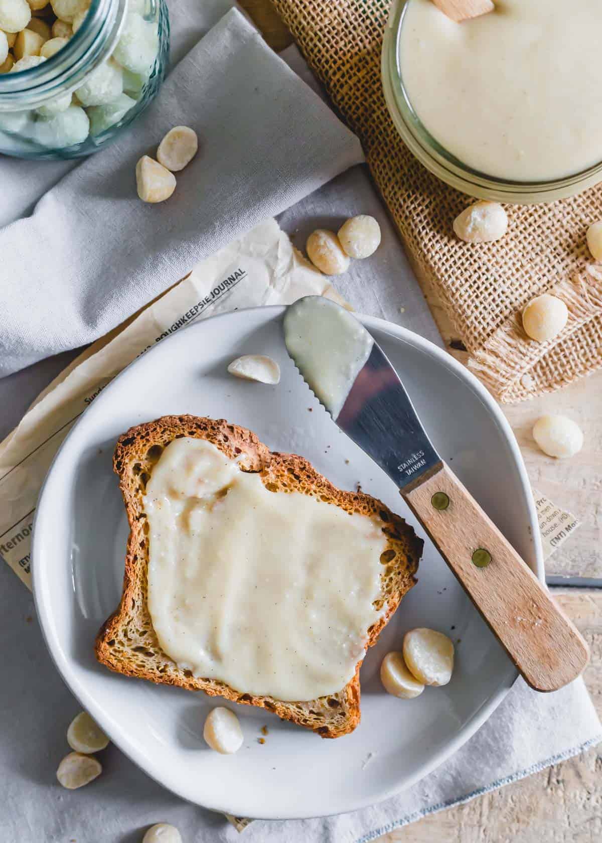 Macadamia butter spread on toast on a plate with a spatula.