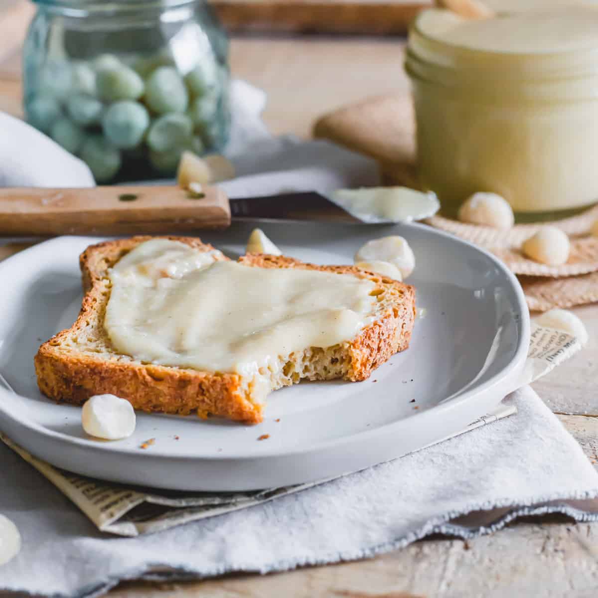 A piece of toast on a plate with macadamia nut butter spread.