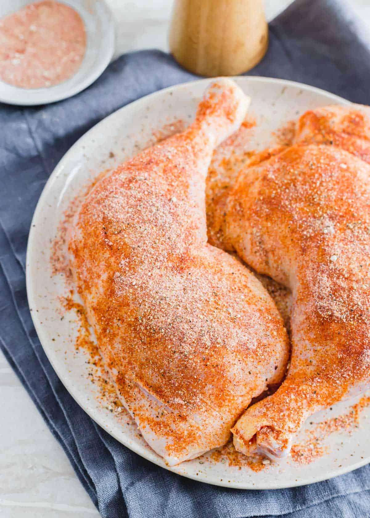 Seasoned chicken leg quarters on a plate.