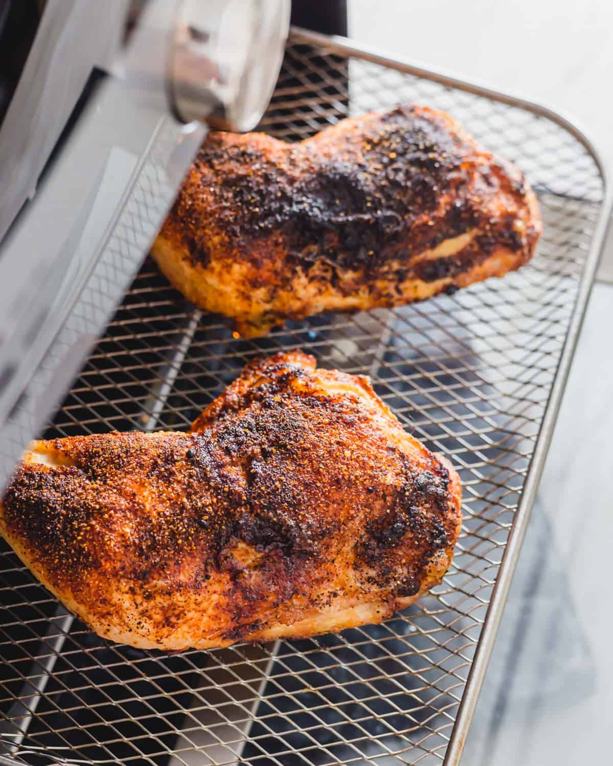 Air fried chicken leg quarters on the tray in an air fryer.