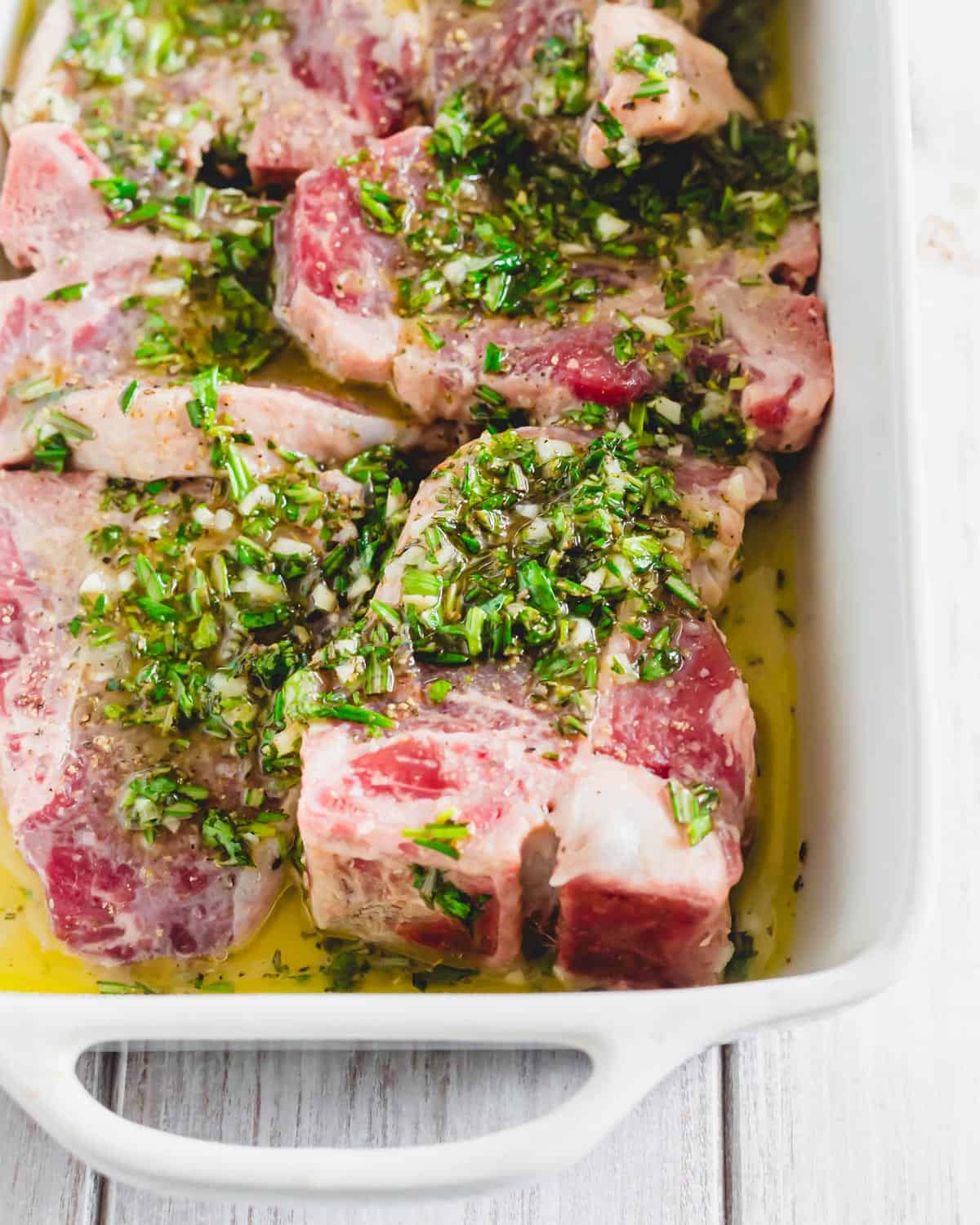 Marinating lamb chops in a white baking dish.