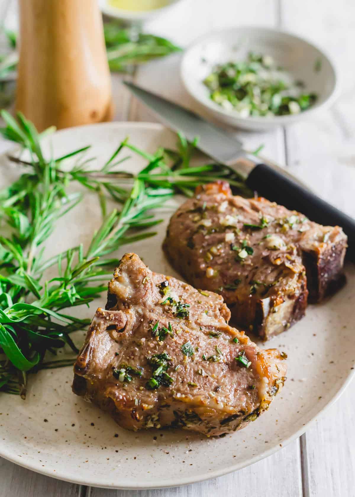 Air fryer lamb chops on a plate with rosemary sprigs.