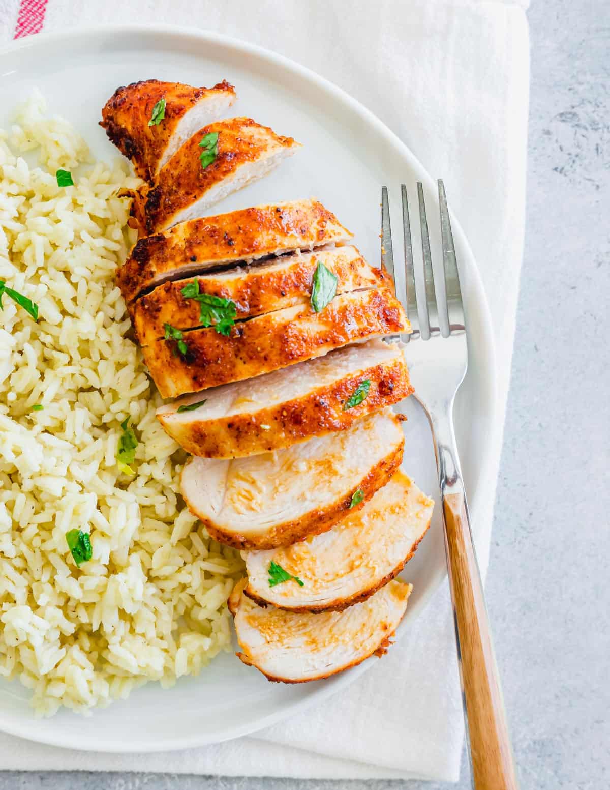 Air Fryer Frozen Chicken Breasts sliced on a plate with rice.