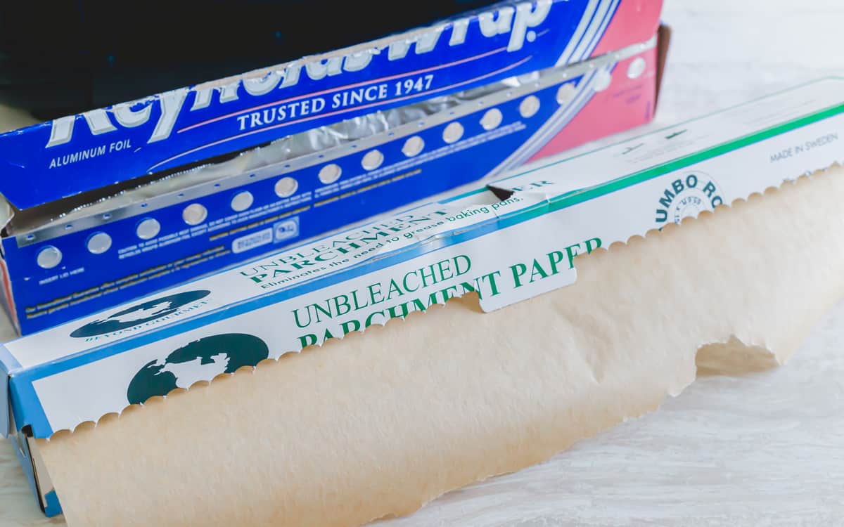 Unbleached parchment paper and aluminum foil next to an air fryer.