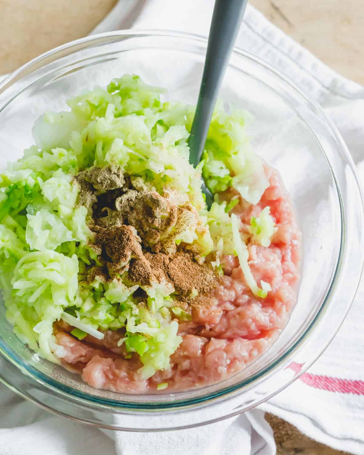 Ground chicken sausage patty ingredients in a glass bowl.