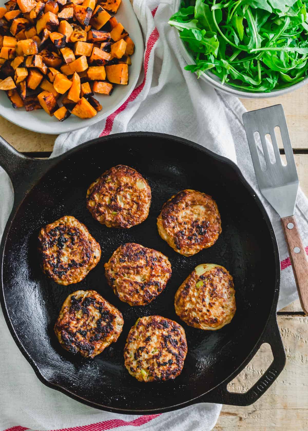 Cooked breakfast chicken sausage patties in a cast iron skillet.