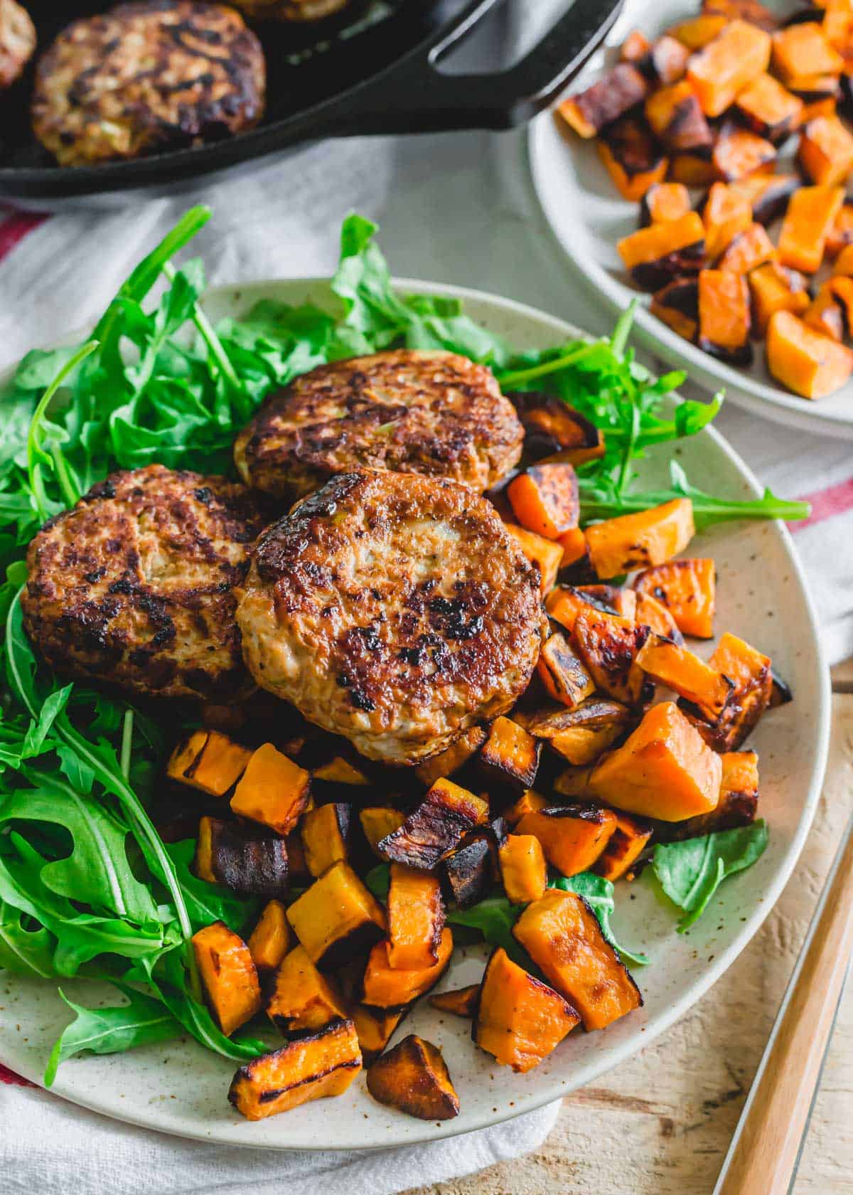 Homemade ground chicken sausage patties served with skillet sweet potatoes and arugula.