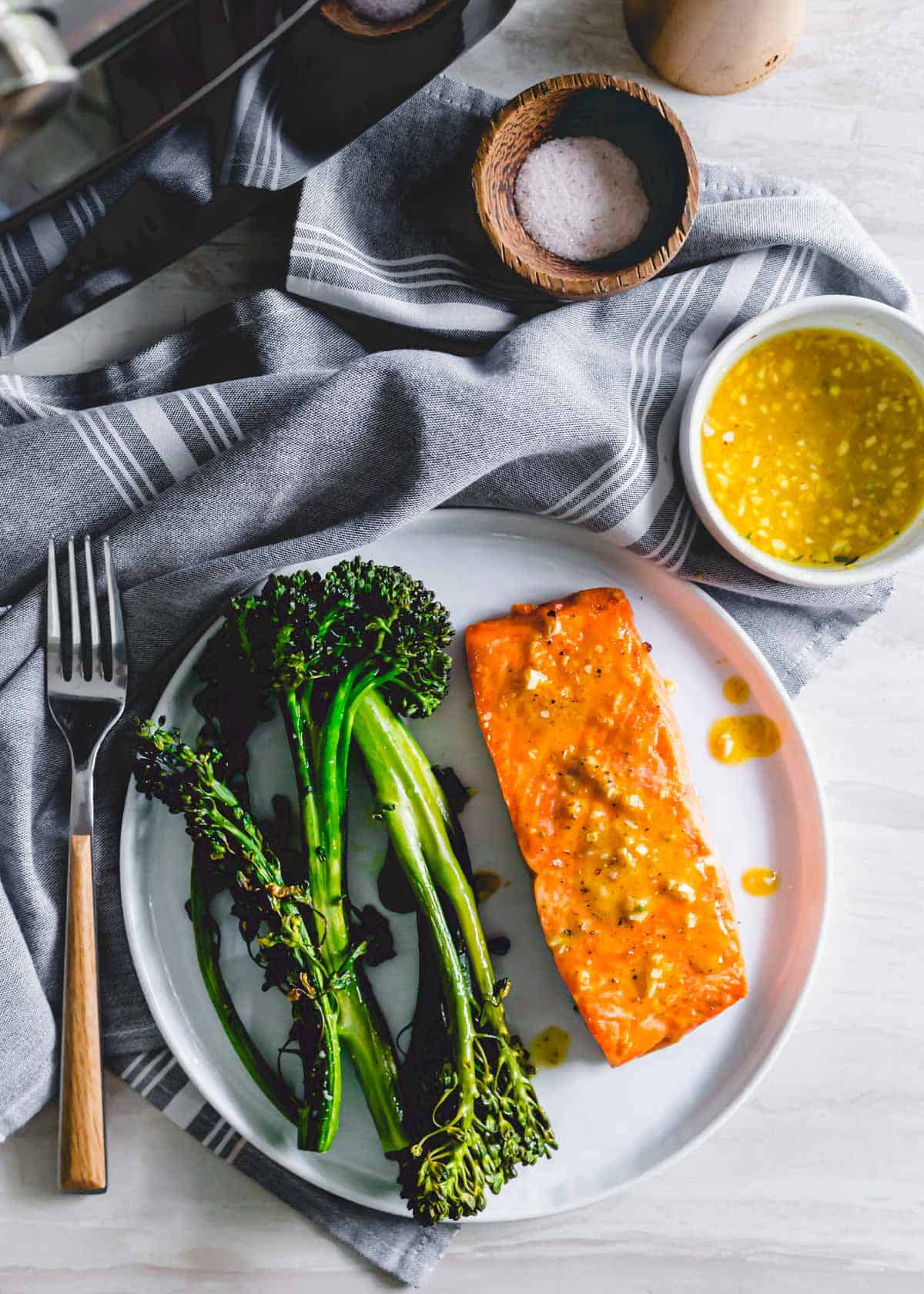 Frozen salmon cooked in an air fryer served with broccolini on a white plate.
