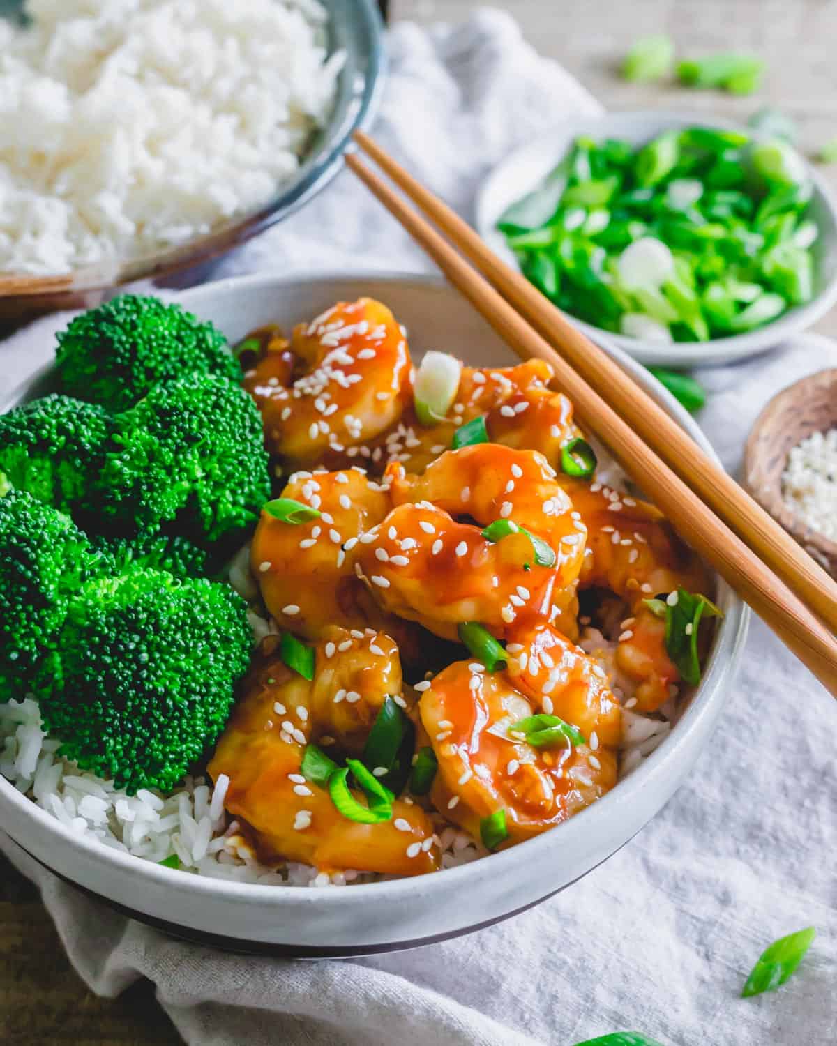 General Tso shrimp in a bowl with broccoli, white rice and chopsticks on the side.