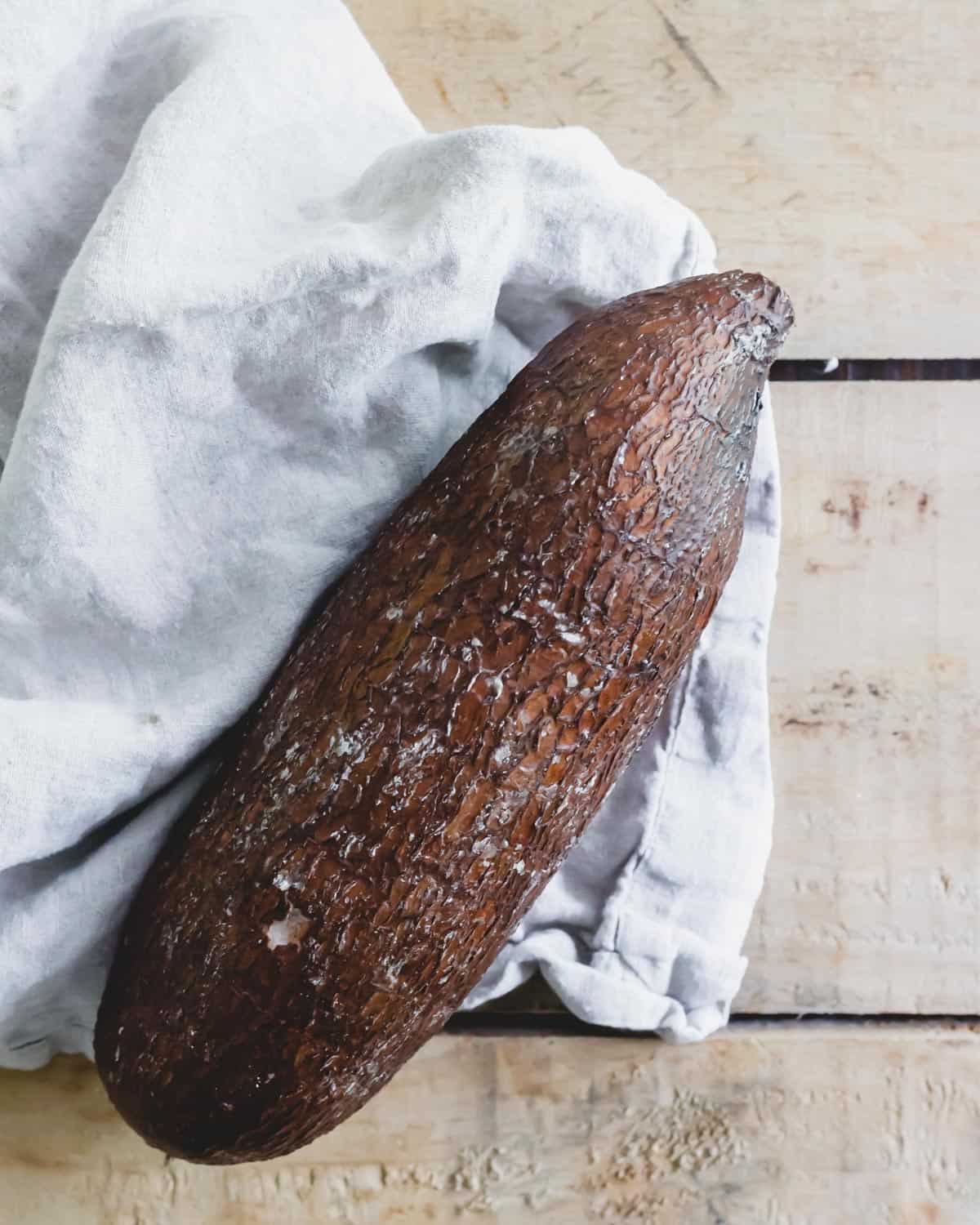 Yuca root on a wood surface with a linen kitchen towel.