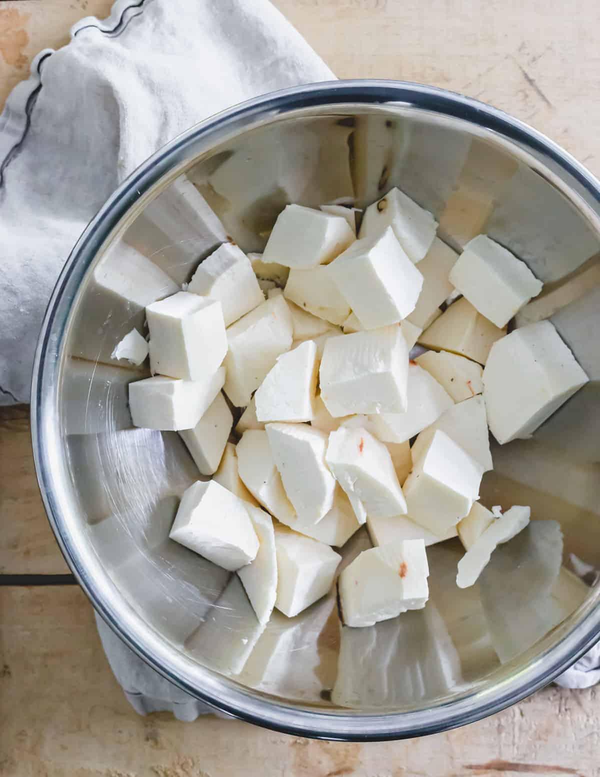 Chopped and peeled yuca root in a metal bowl.