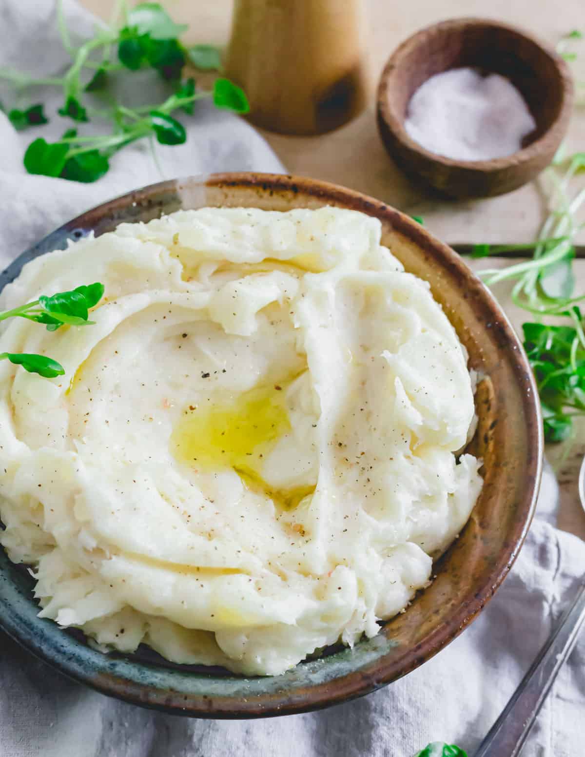 Mashed cassava recipe in a bowl with a puddle of melted ghee in the middle. Seasoned with coarse salt and pepper.