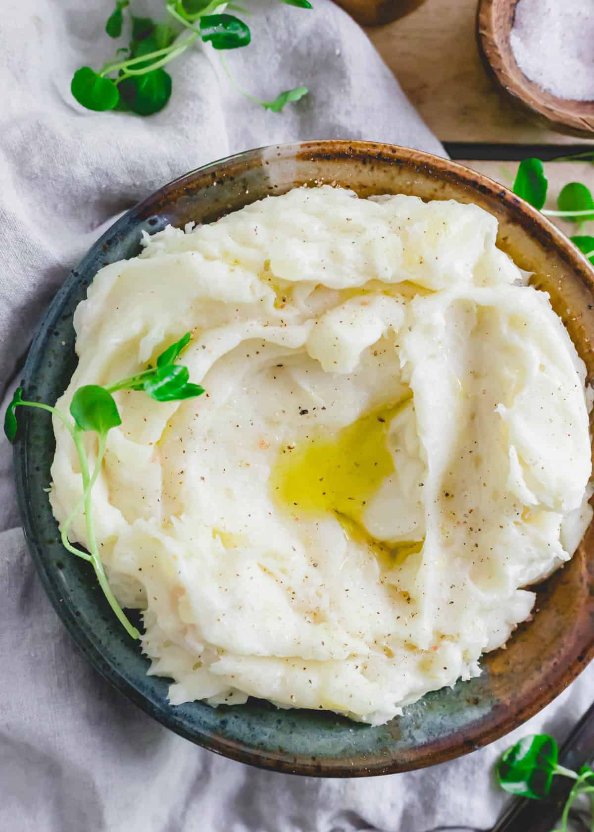 Garlic Mashed Yuca in a bowl topped with melted ghee, salt and pepper.