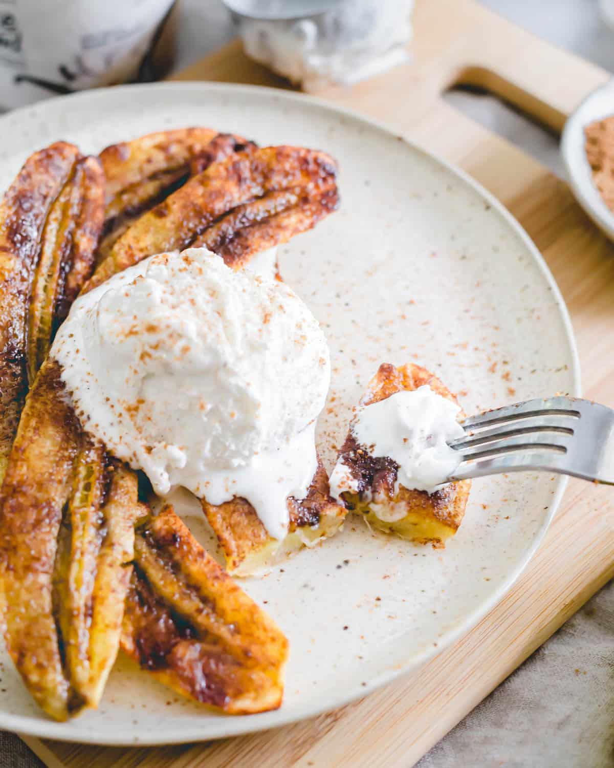 Cinnamon sugar air fryer bananas on a plate with a scoop of vanilla ice cream.