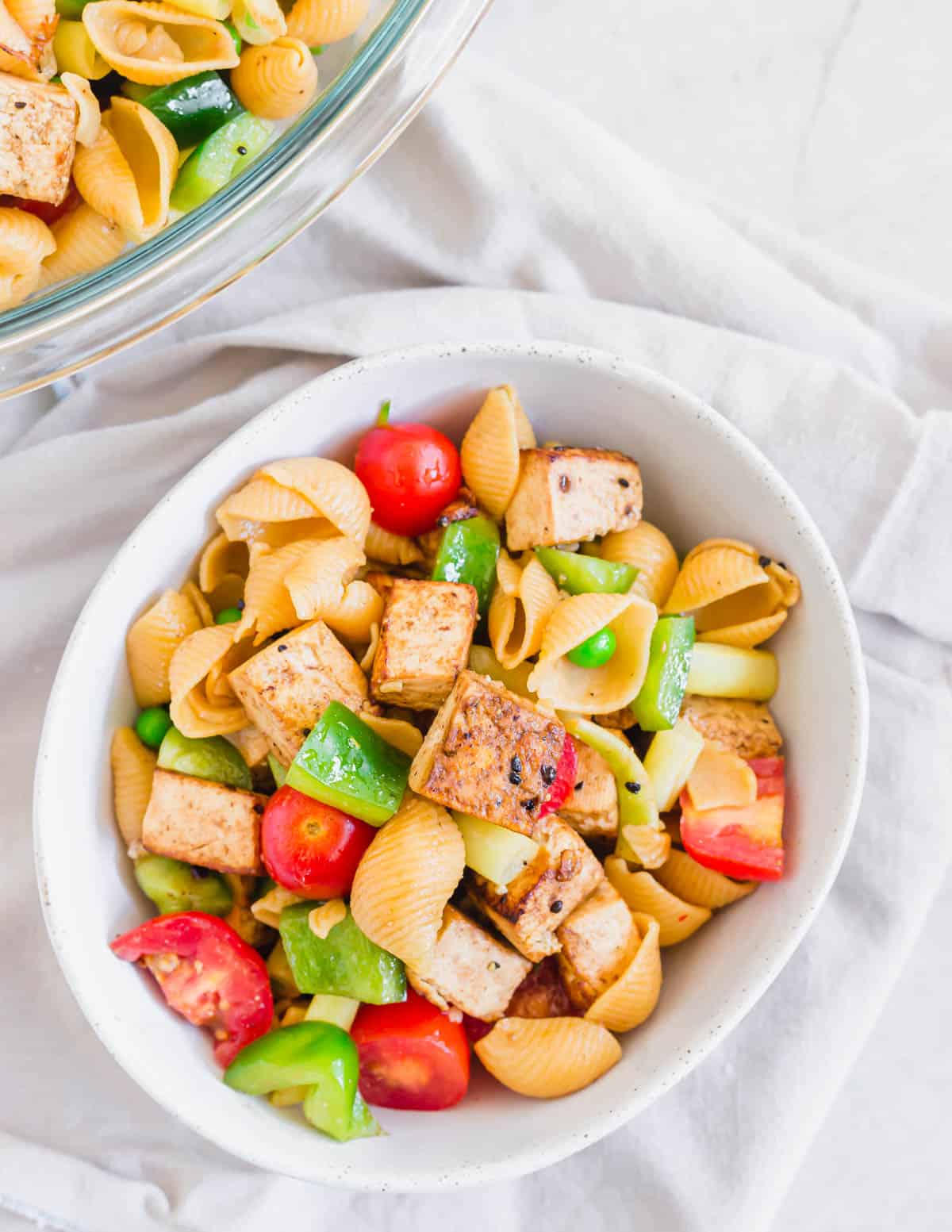 Tofu pasta salad in a bowl on a neutral colored napkin.