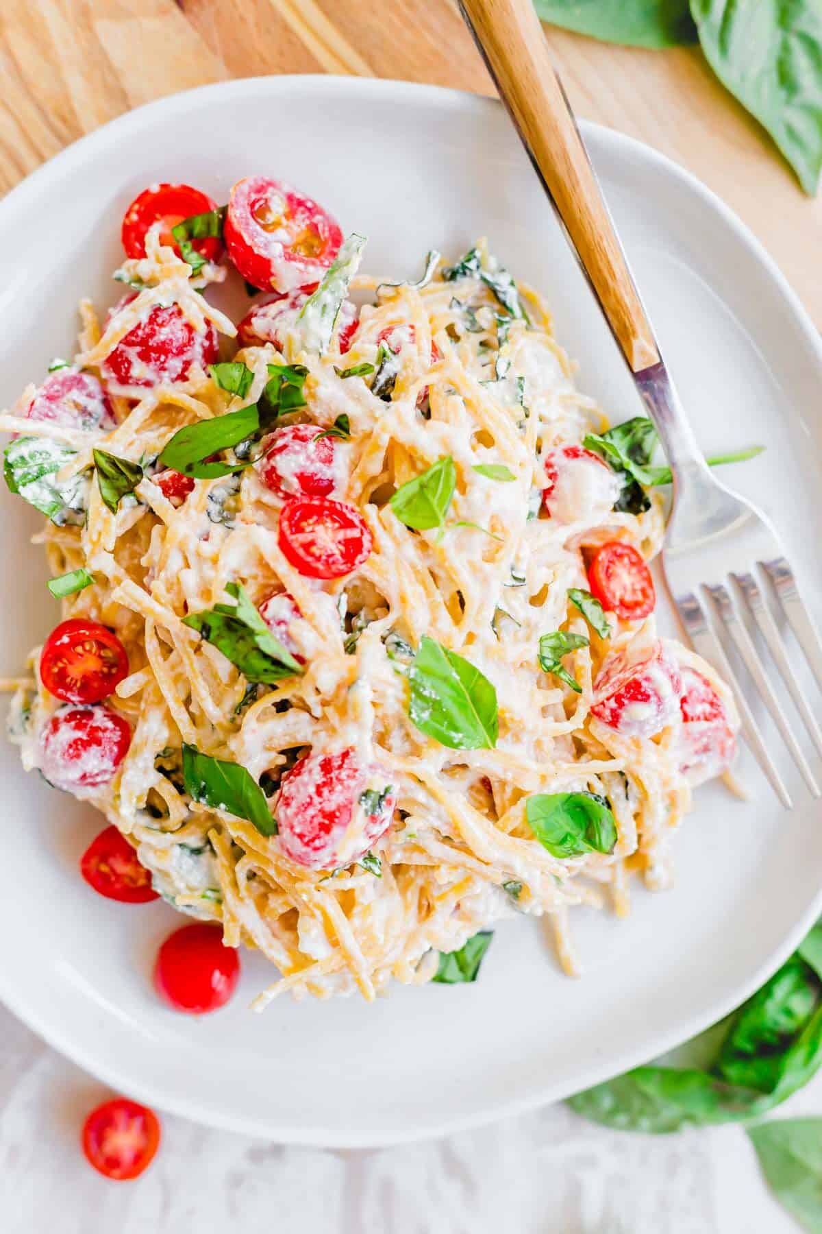 Easy lemon ricotta pasta recipe with cherry tomatoes and basil on a plate with a fork on the side.