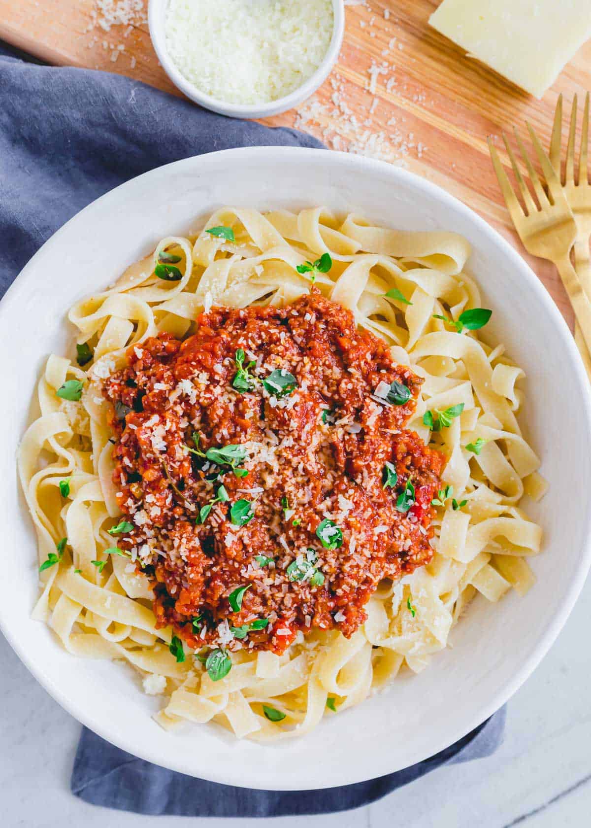 A bowl of cooked tagliatelle pasta noodles with lamb bolognese spooned over top.