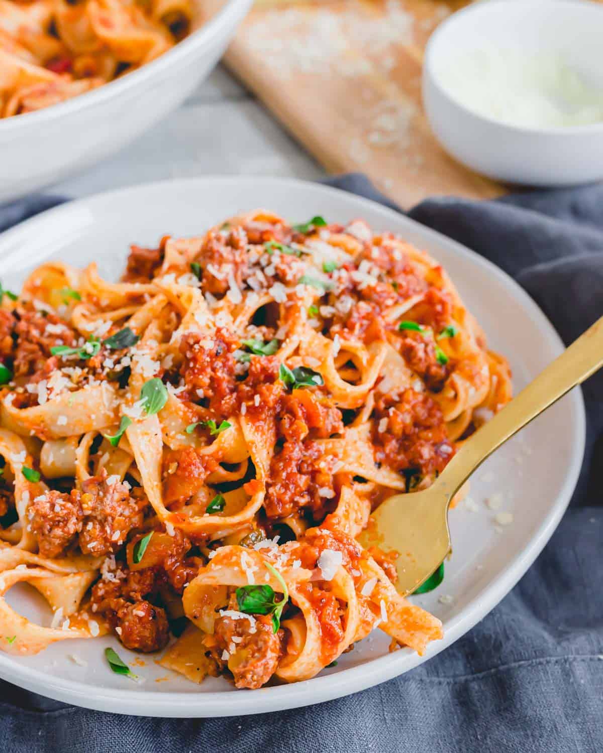 Easy lamb bolognese recipe on a plate with noodles twirled around a fork.