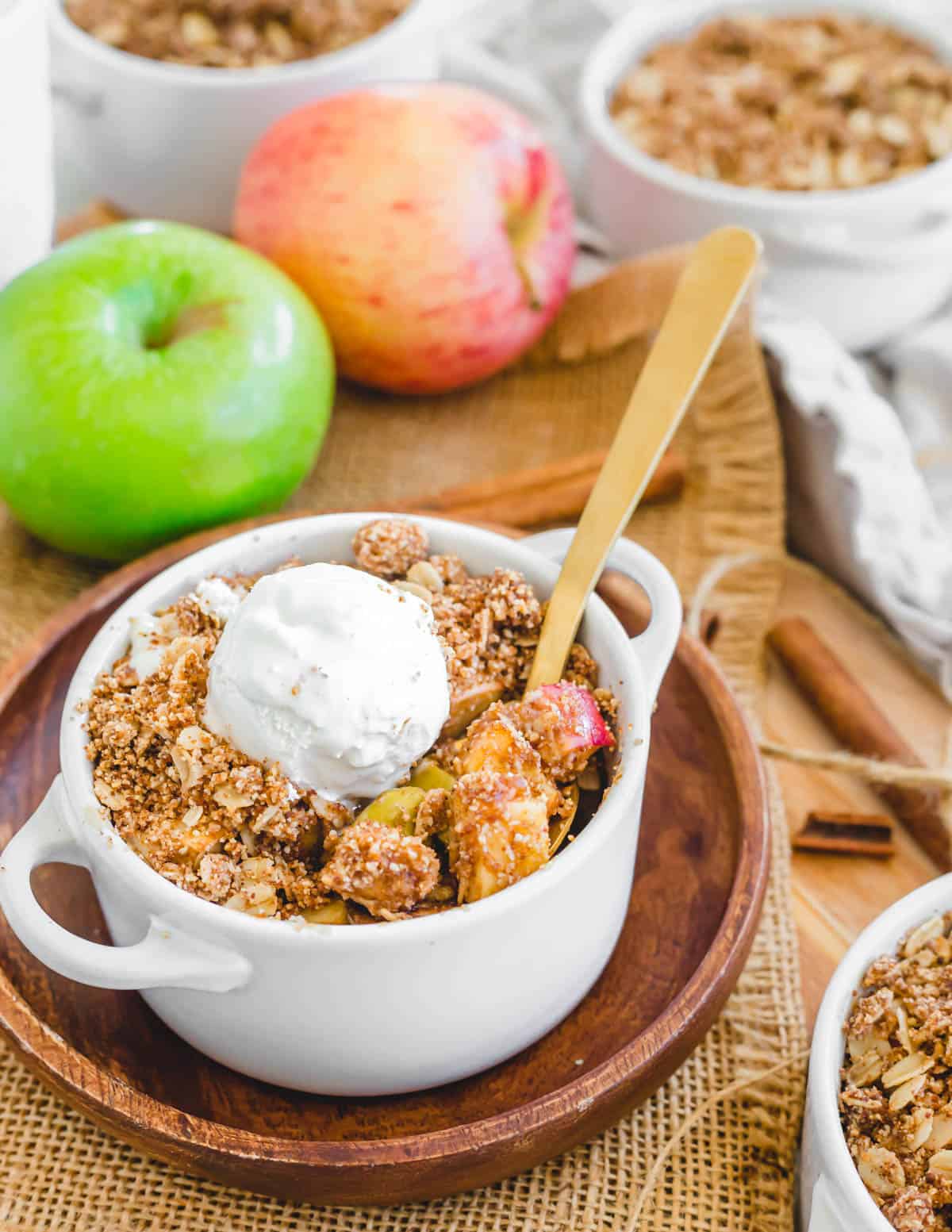 Gluten-free and vegan apple crisp made in the air fryer with a scoop of vanilla ice cream on top and a serving spoon.