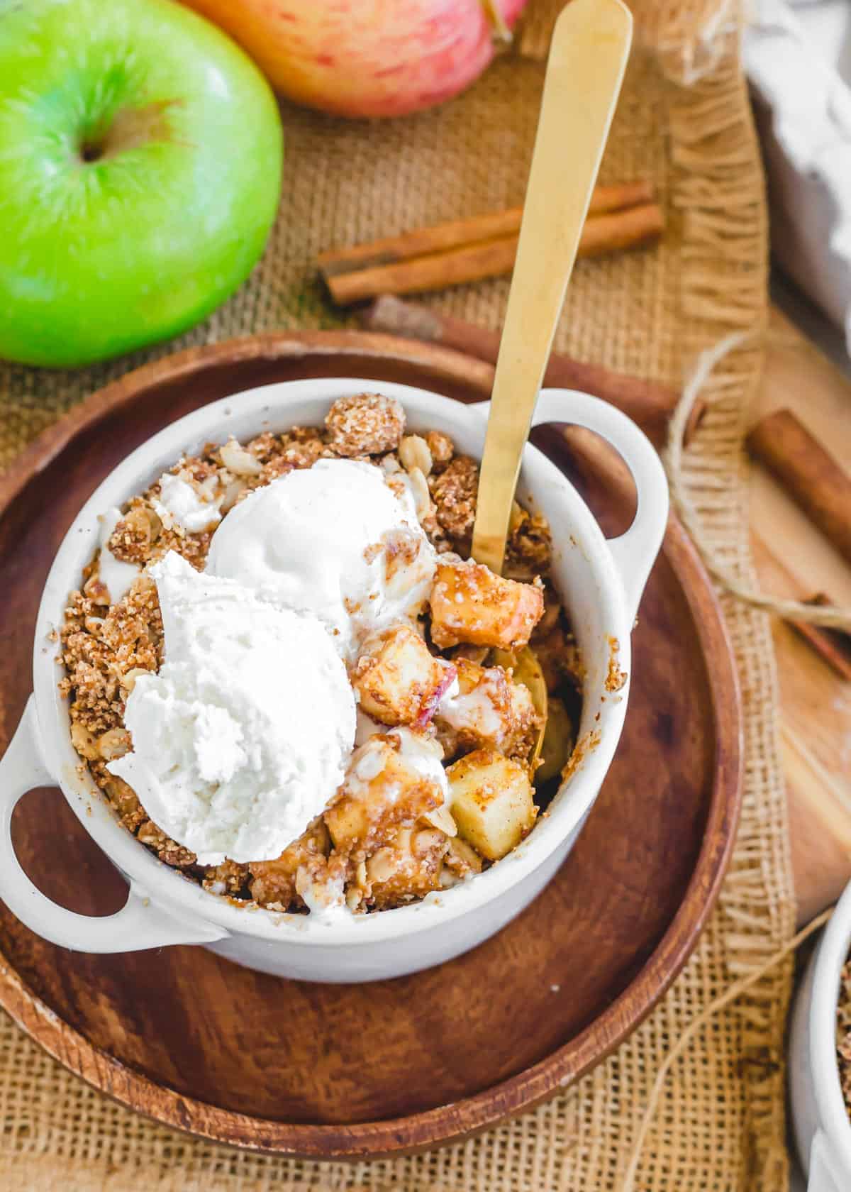 Air fryer apple crisp in a white ramekin with vanilla ice cream on top.