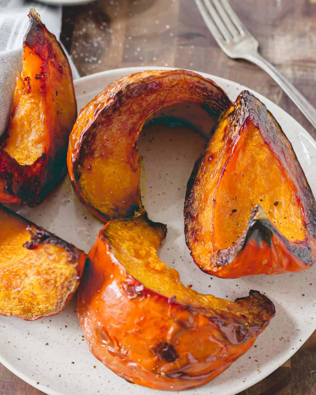 Roasted red kuri squash wedges on a plate.