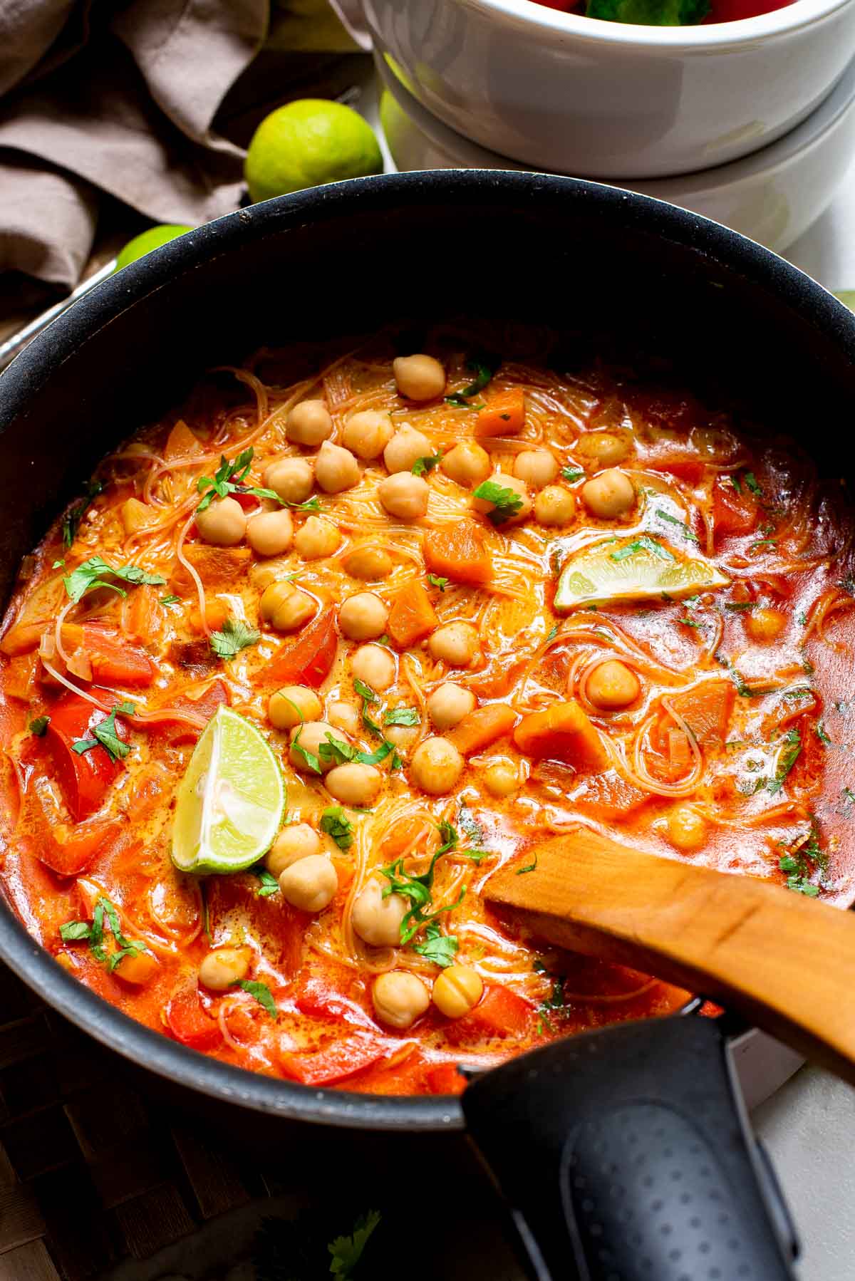 Vegetarian red curry soup with chickpeas in a black pot with a serving spoon.