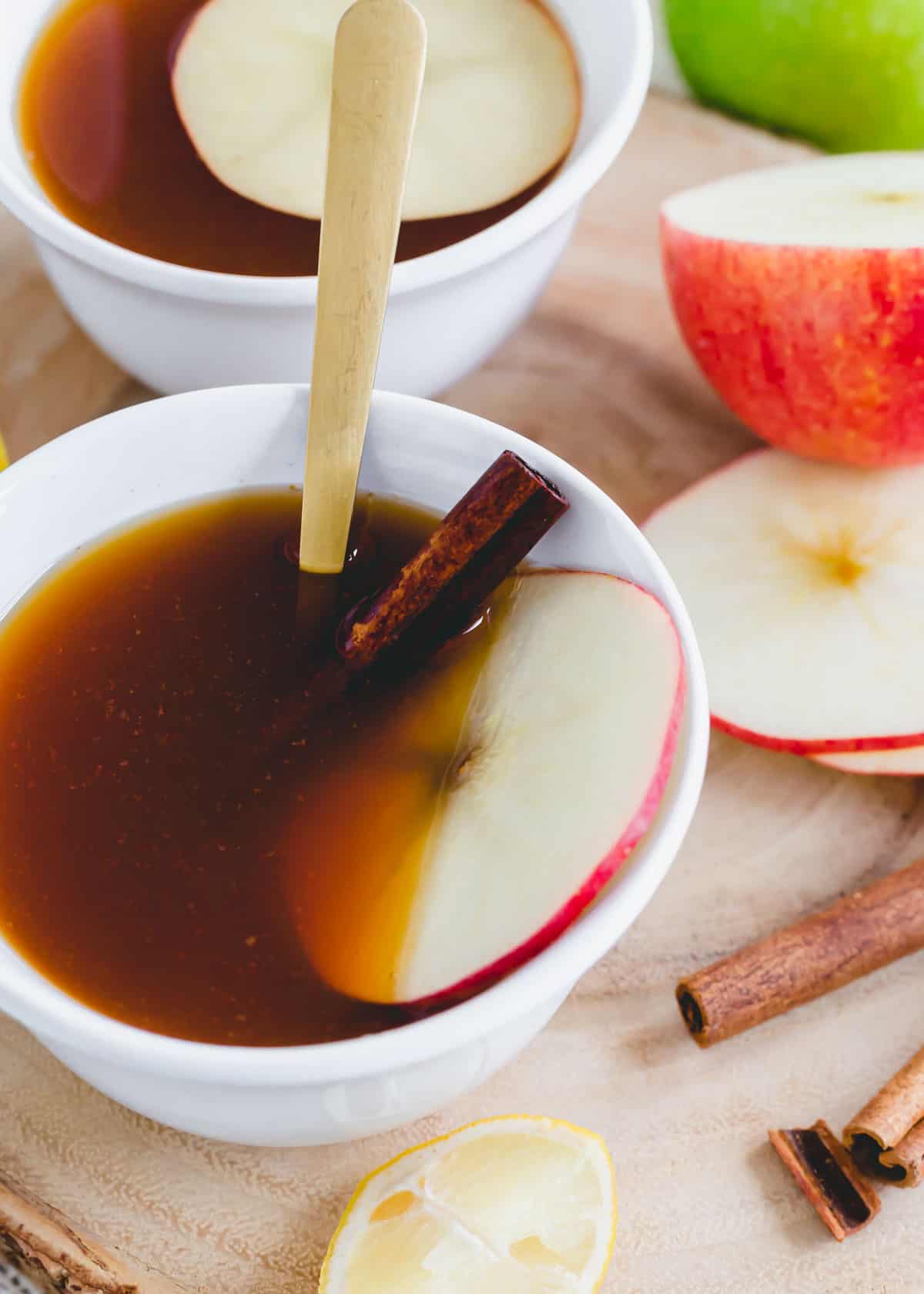 Warm apple cider tea with cinnamon garnished with an apple slice in a mug.