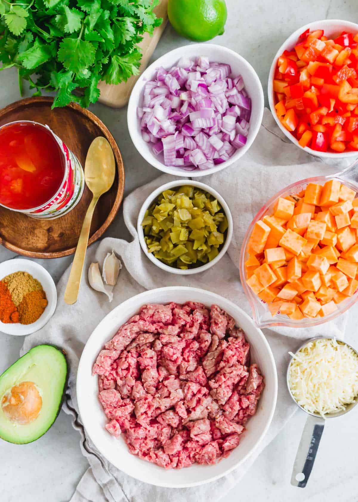 Prepped ingredients in bowls to make a ground beef sweet potato recipe on the stovetop.