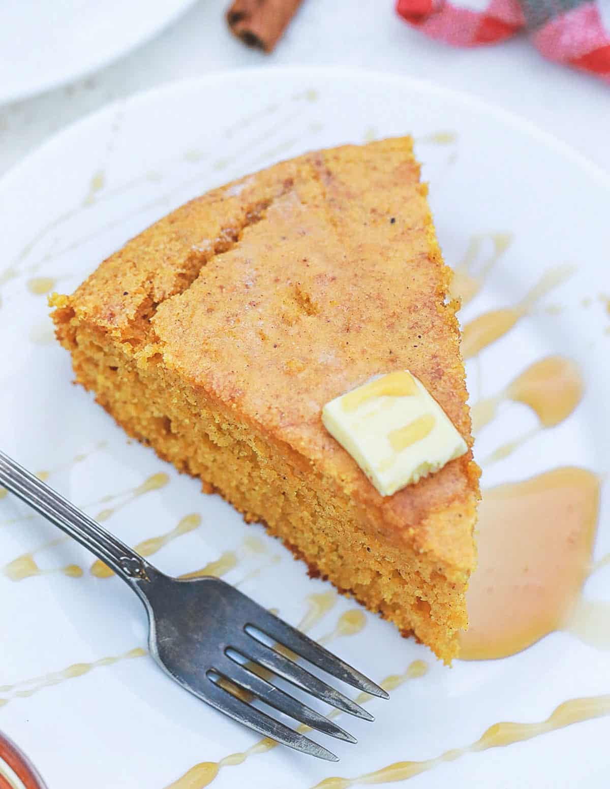 Sweet potato cornbread served with maple syrup and butter on a white plate.