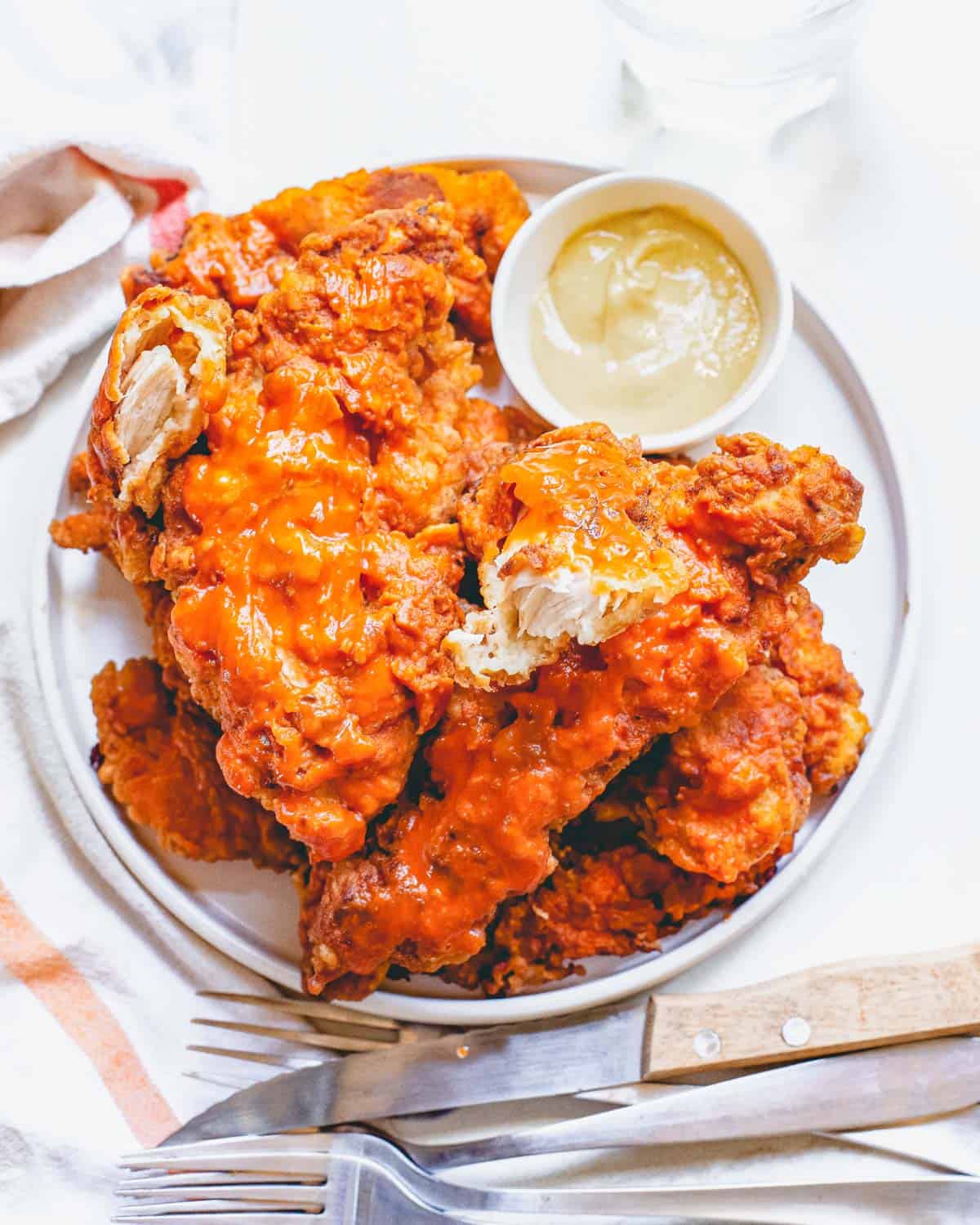 Air fryer buffalo chicken recipe piled on a plate served with a dipping sauce.