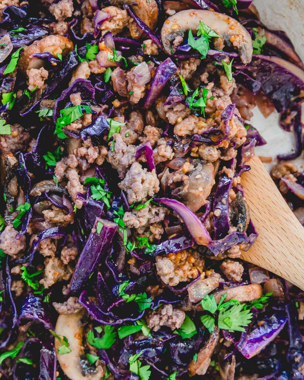 Pork with cabbage stir fry tossed with an Asian almond butter soy sauce in a skillet.