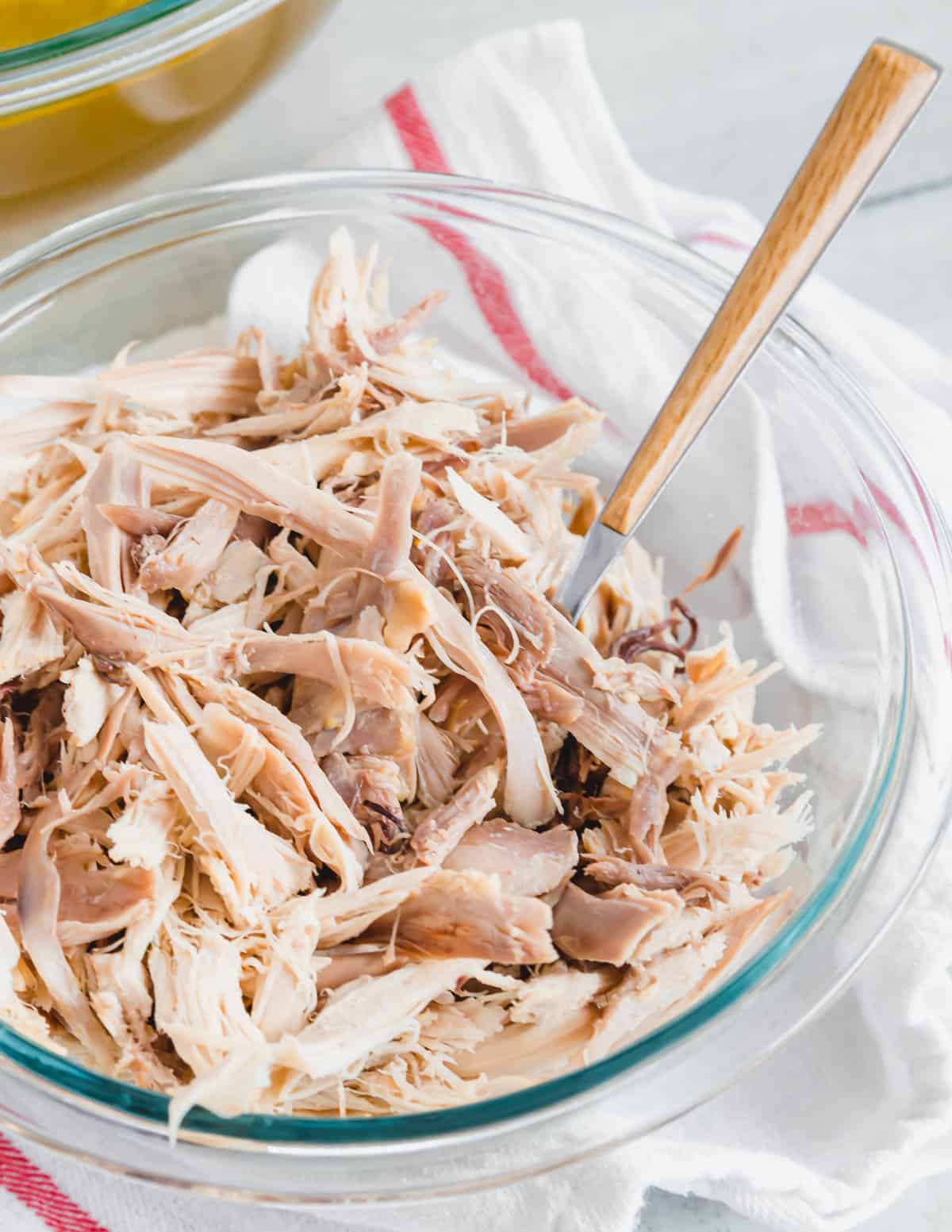 Stewing hen meat cooked in an Instant Pot shredded in a glass bowl.