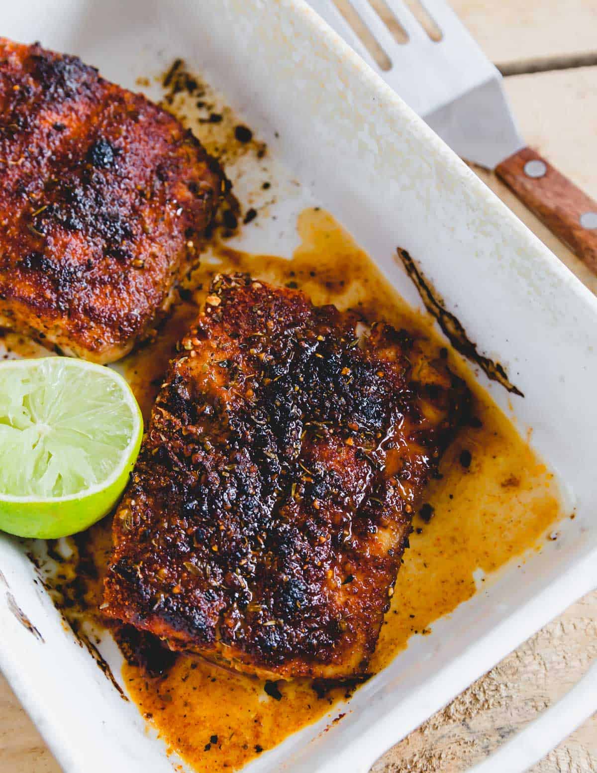 Broiled blackened mahi mahi in a baking dish with a half a lime.