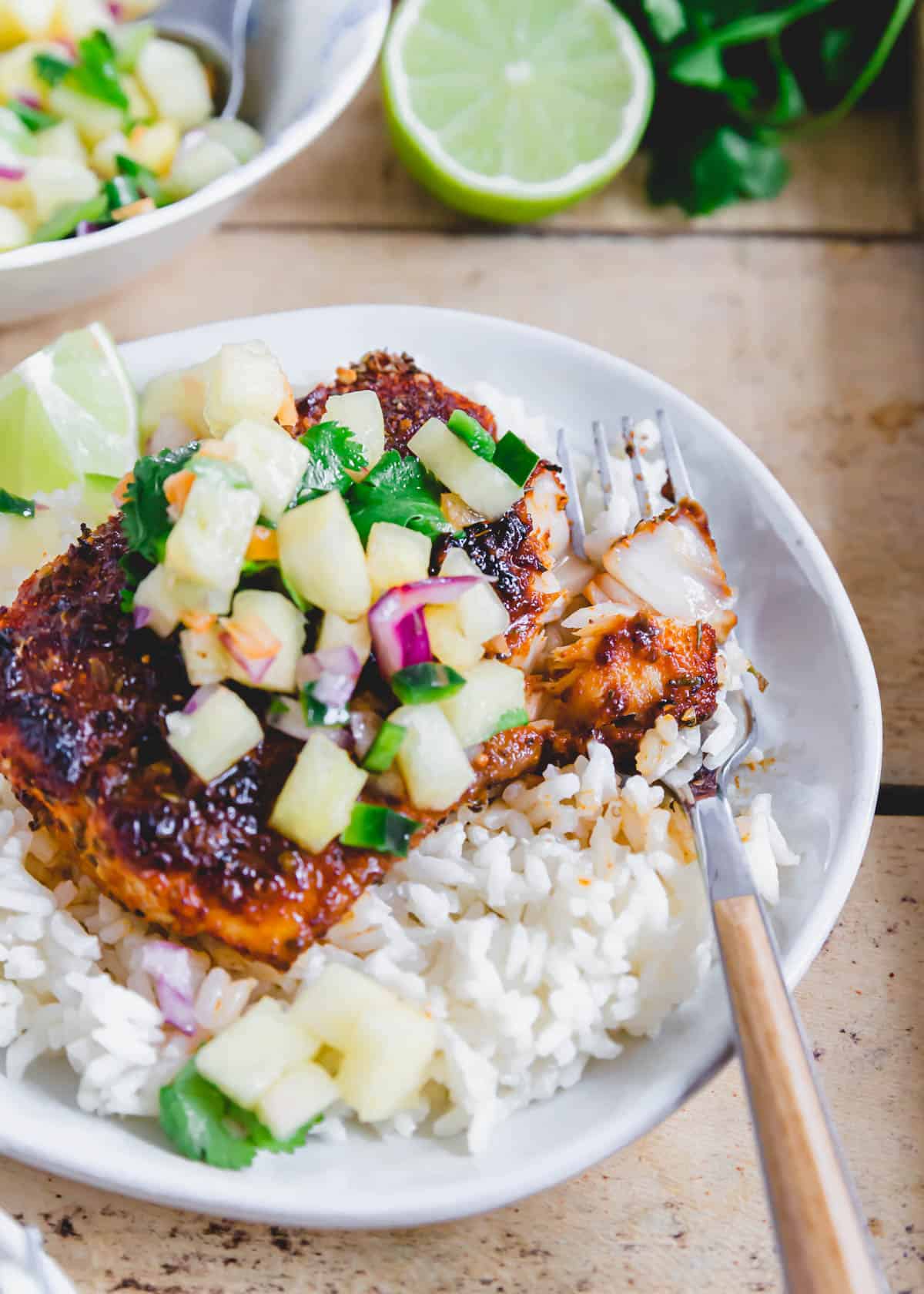 Blackened mahi mahi recipe served with pineapple salsa and rice on a plate with a fork.