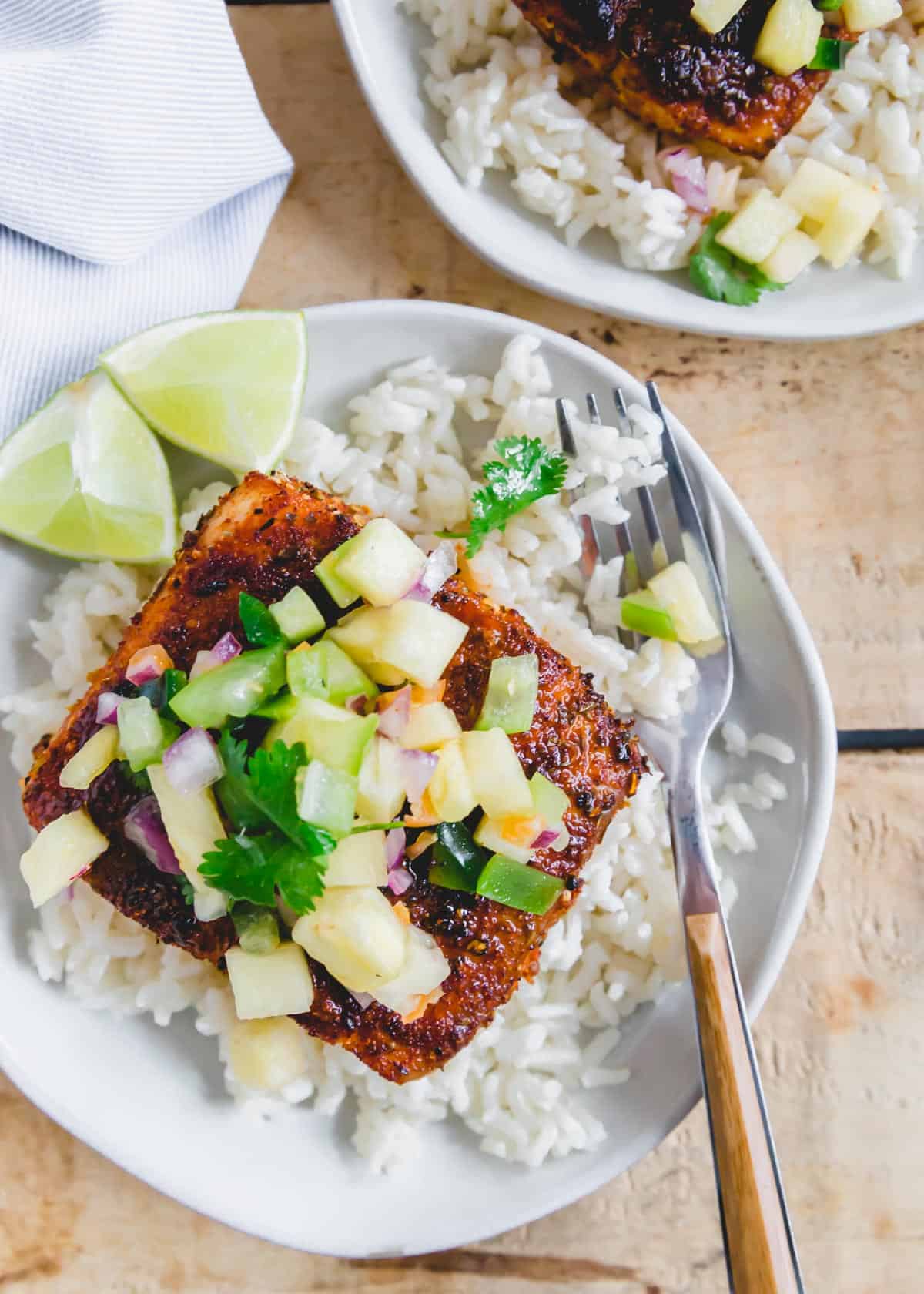 Blackened Mahi Mahi with pineapple habanero salsa served over rice on a white plate with a fork.