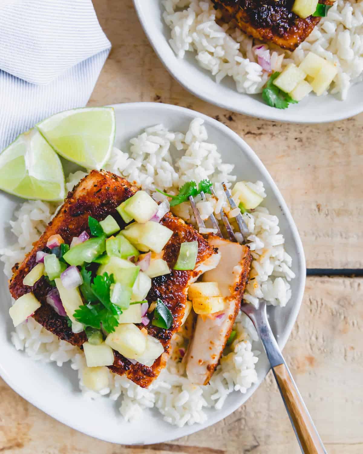 Mahi mahi filet with blackening seasoning broiled until flaky on a plate with rice and salsa.