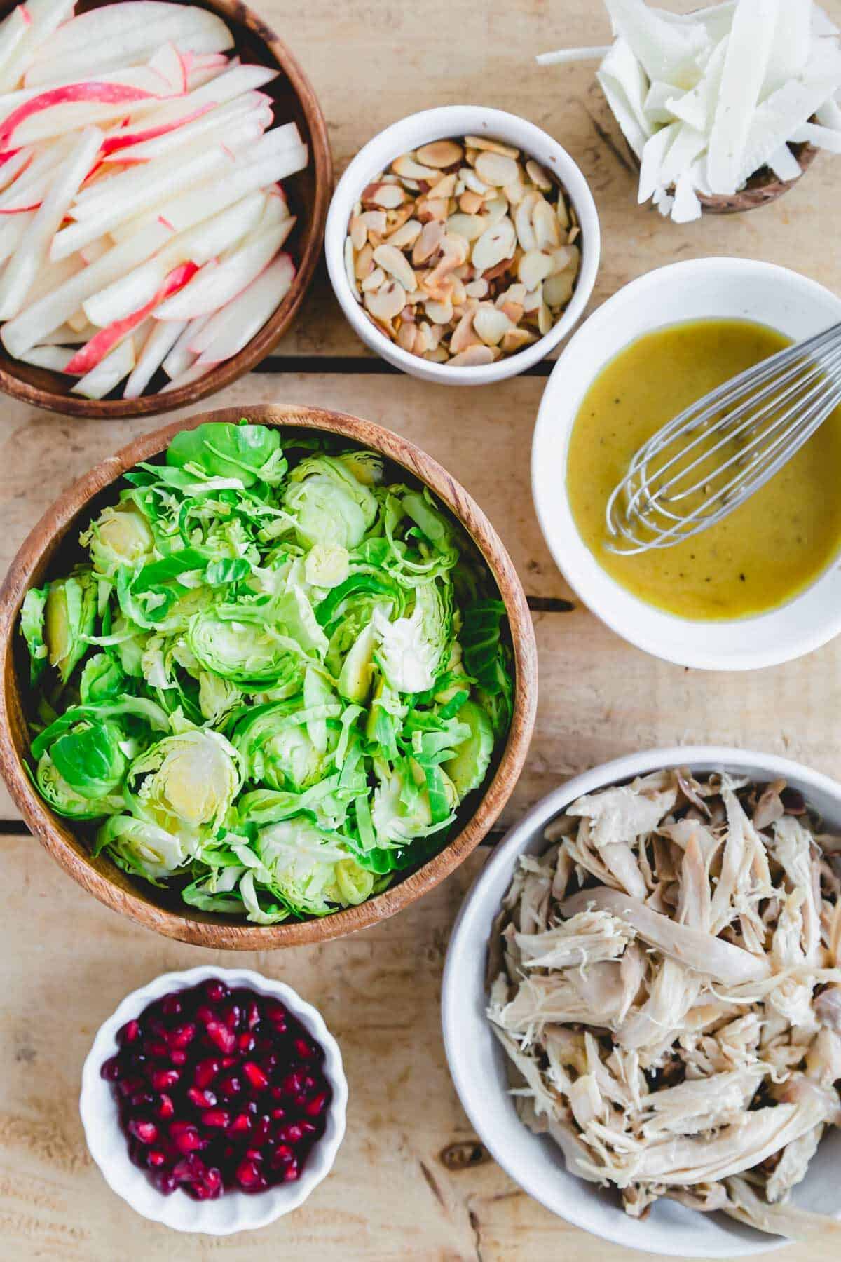 Ingredients to make Brussels sprouts and chicken salad with honey mustard dressing in bowls.