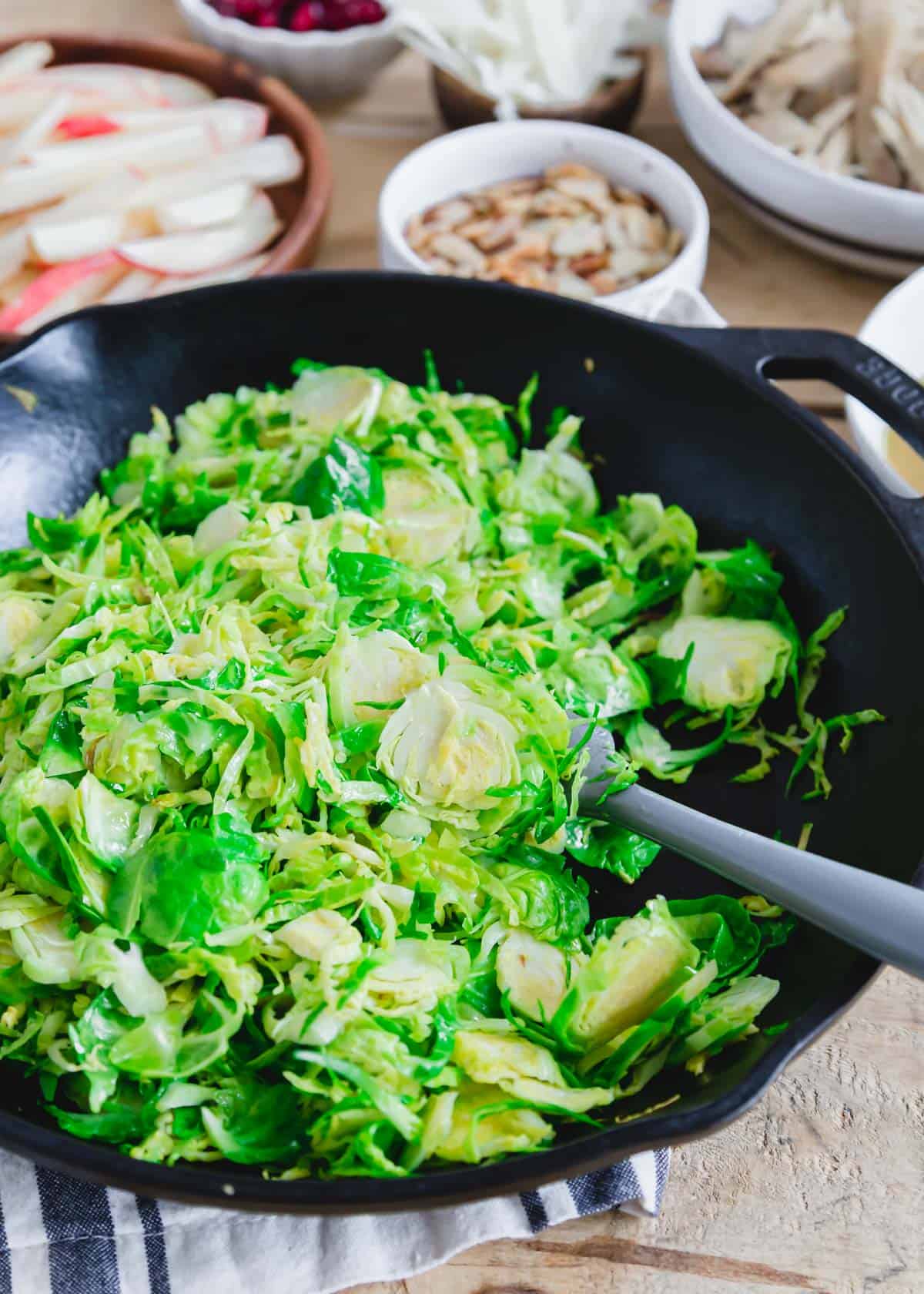 Shredded Brussels sprouts cooking in a black cast iron skillet.