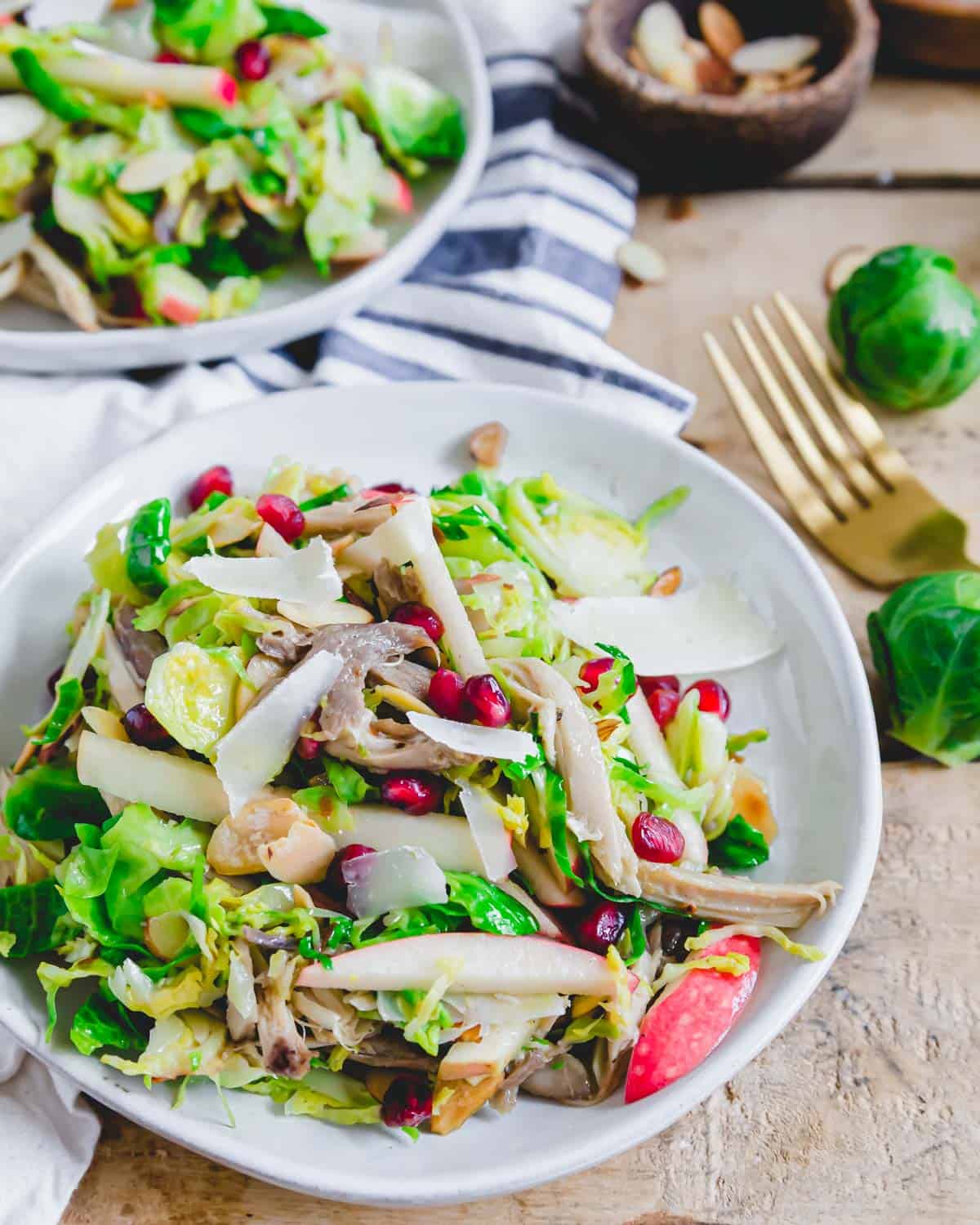 Honey mustard chicken brussels sprouts salad on a white plate with pecorino romano shavings.