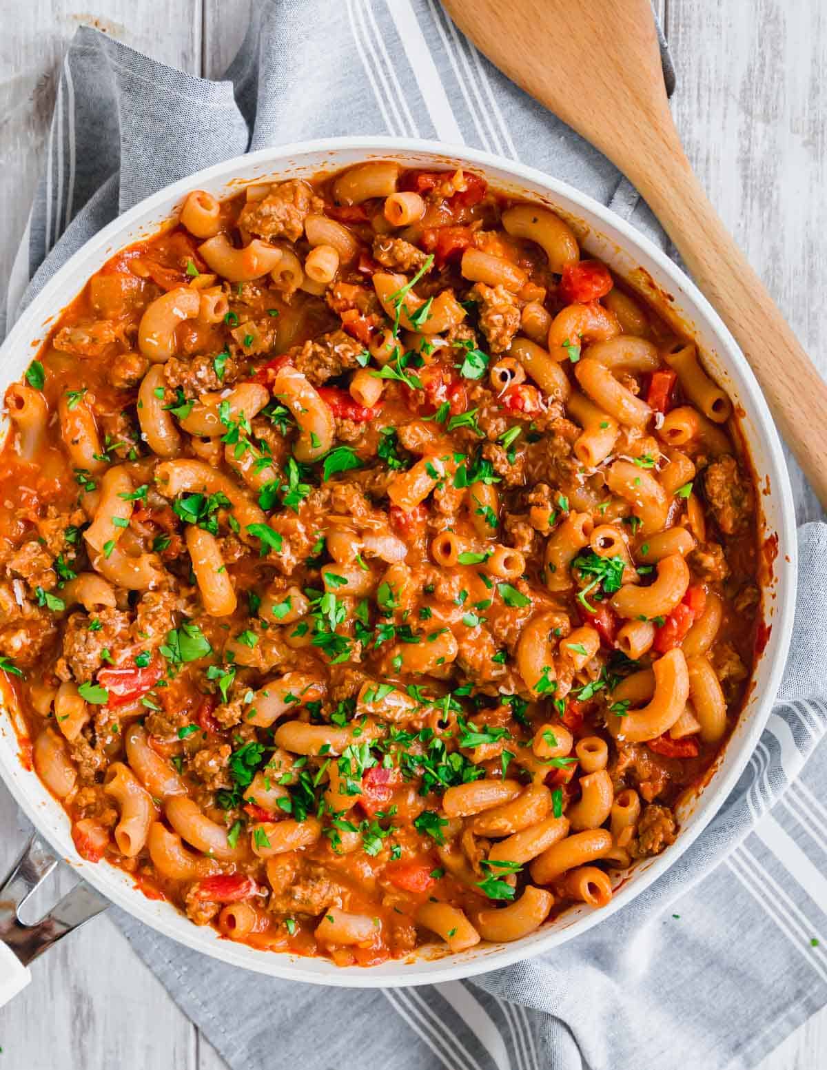 Ground beef with elbow pasta in skillet topped with parsley.