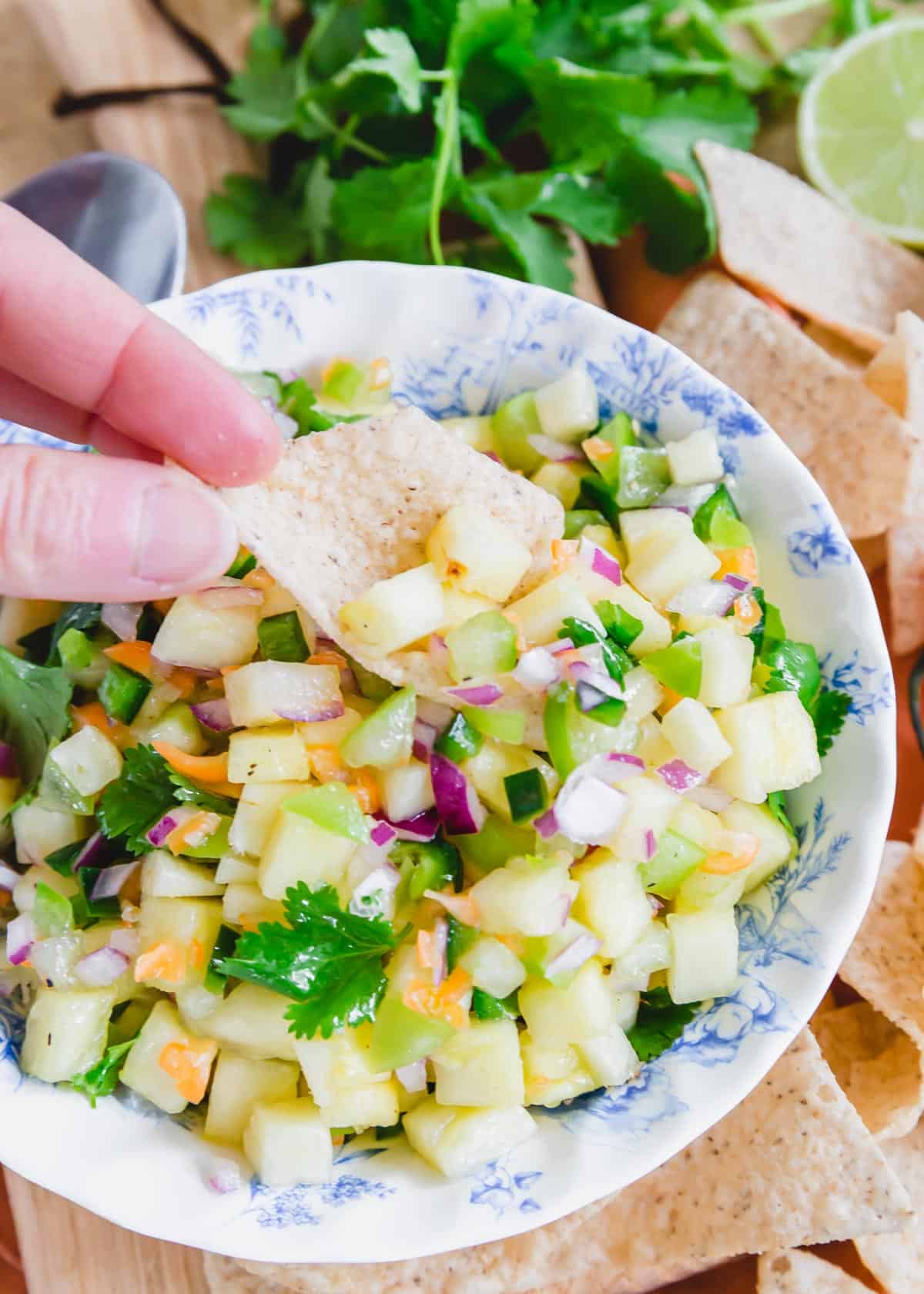 Scooping pineapple habanero pepper salsa with a tortilla chip.