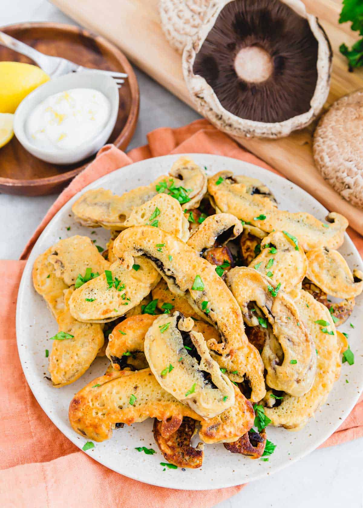 Portobello mushroom fries garnished with parsley on a white speckled plate.