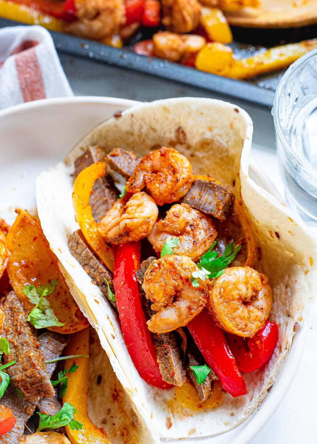 Steak and shrimp fajitas made made on a sheet pan.