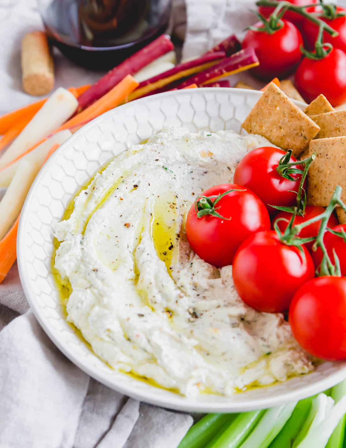 Roasted garlic whipped goat cheese dip in a bowl with cherry tomatoes.