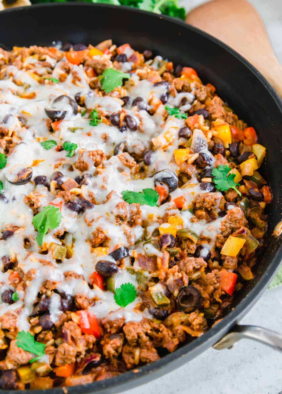 Ground beef Mexican recipe with beans, rice, peppers and melted cheese.